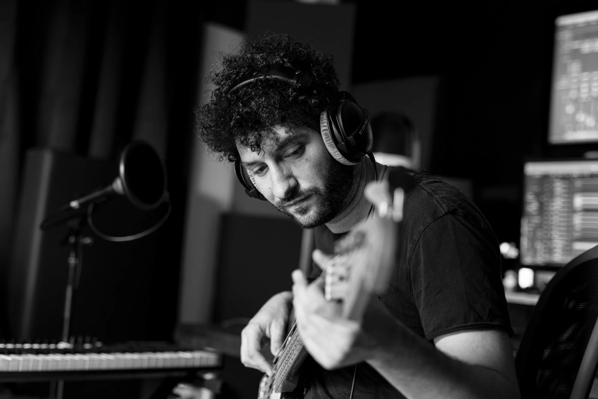 A black and white photo of Billy Lockett, playing an acoustic guitar in recording studio.