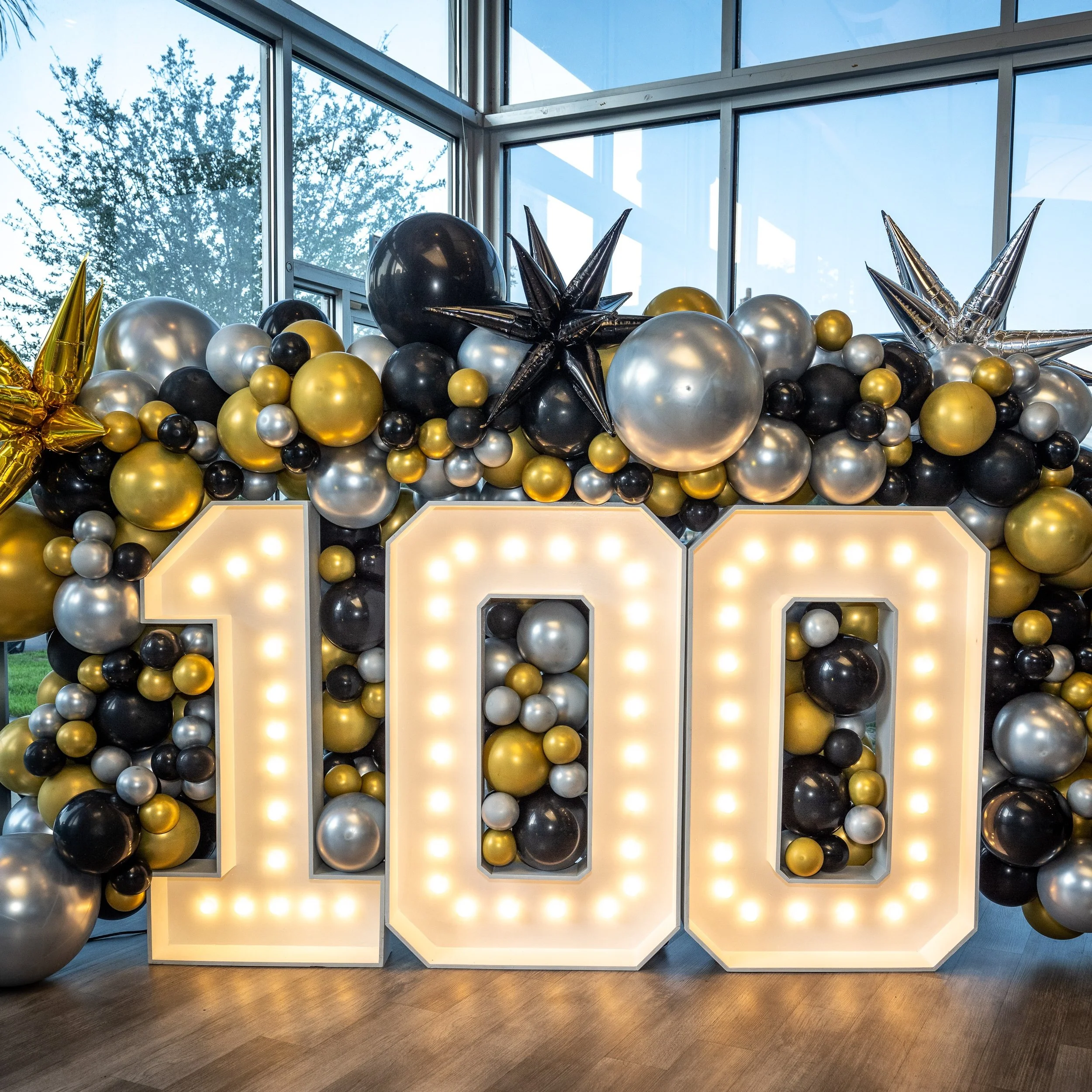 100 YEAR ANNIVERSARY MARQUEE SET UP WITH FULL GOLD, BLACK AND SILVER BALLOON FILL