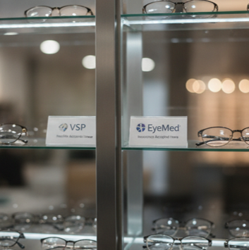 Eyewear display case with several pairs of eyeglasses and signs for VSP and EyeMed vision insurance.