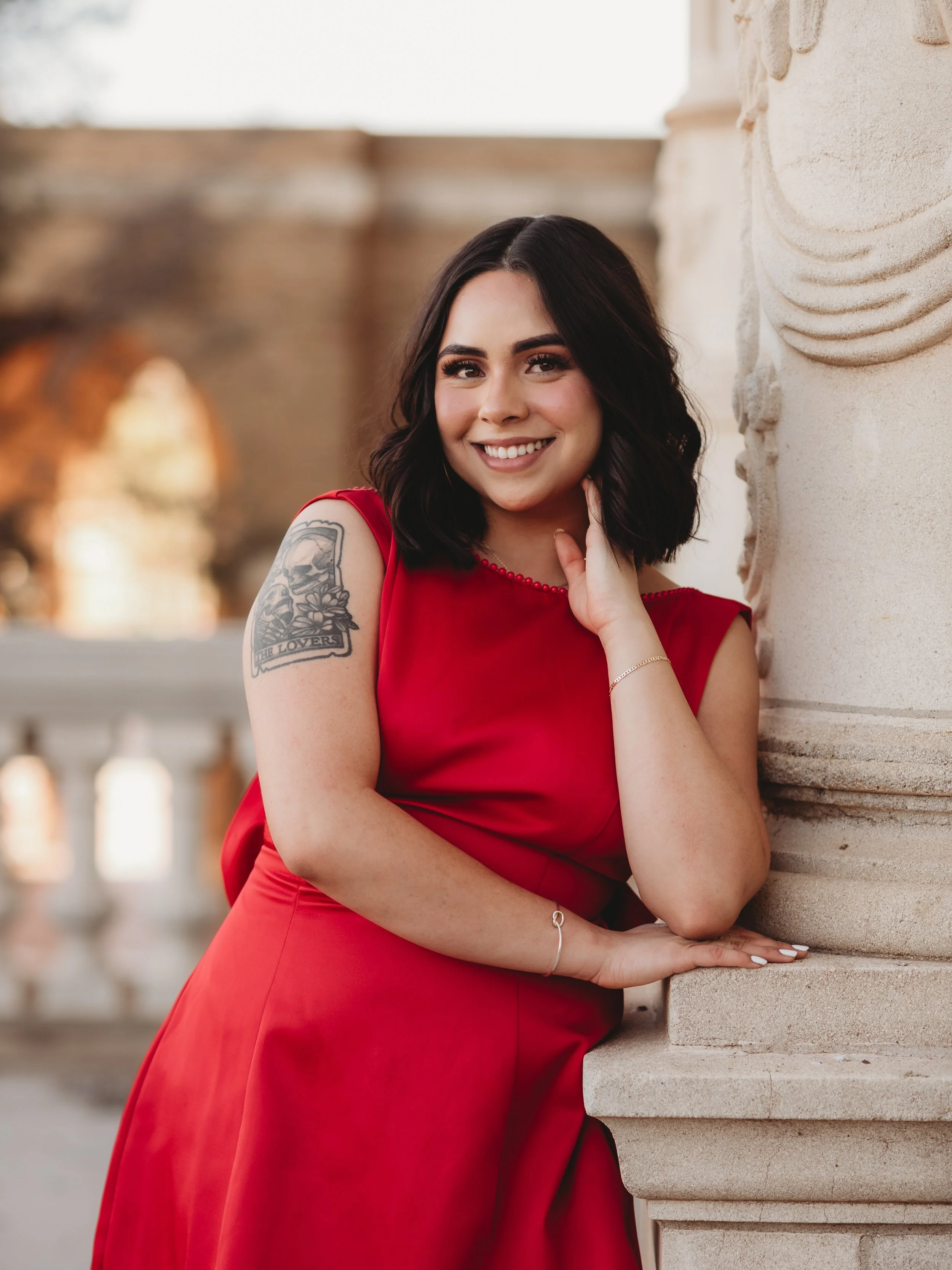 Sam Jurney, graphic designer and brand strategist based in Lubbock, Texas, smiling in a red dress