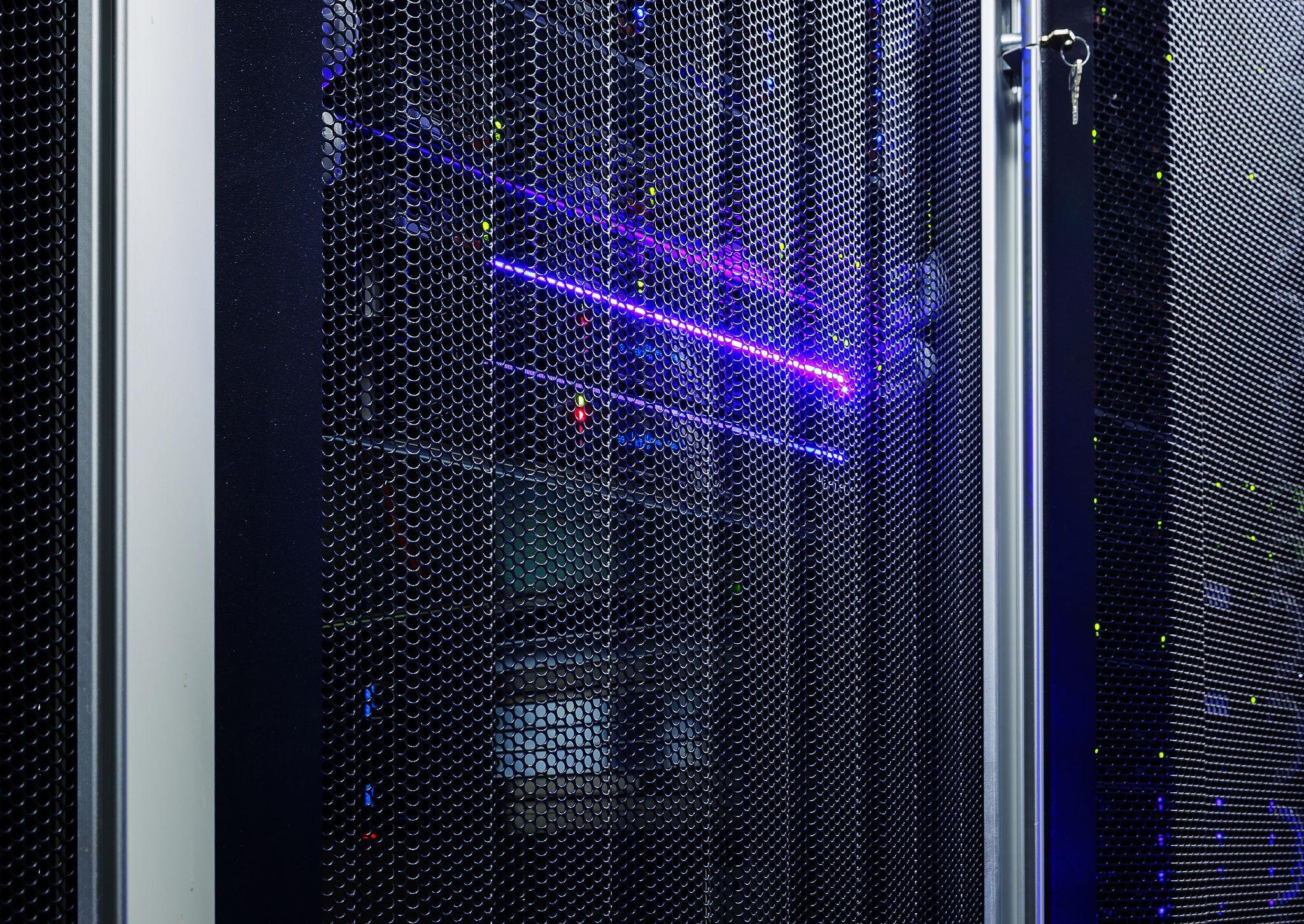 A data center server rack enclosed in a metal mesh door with purple and green LED lights.