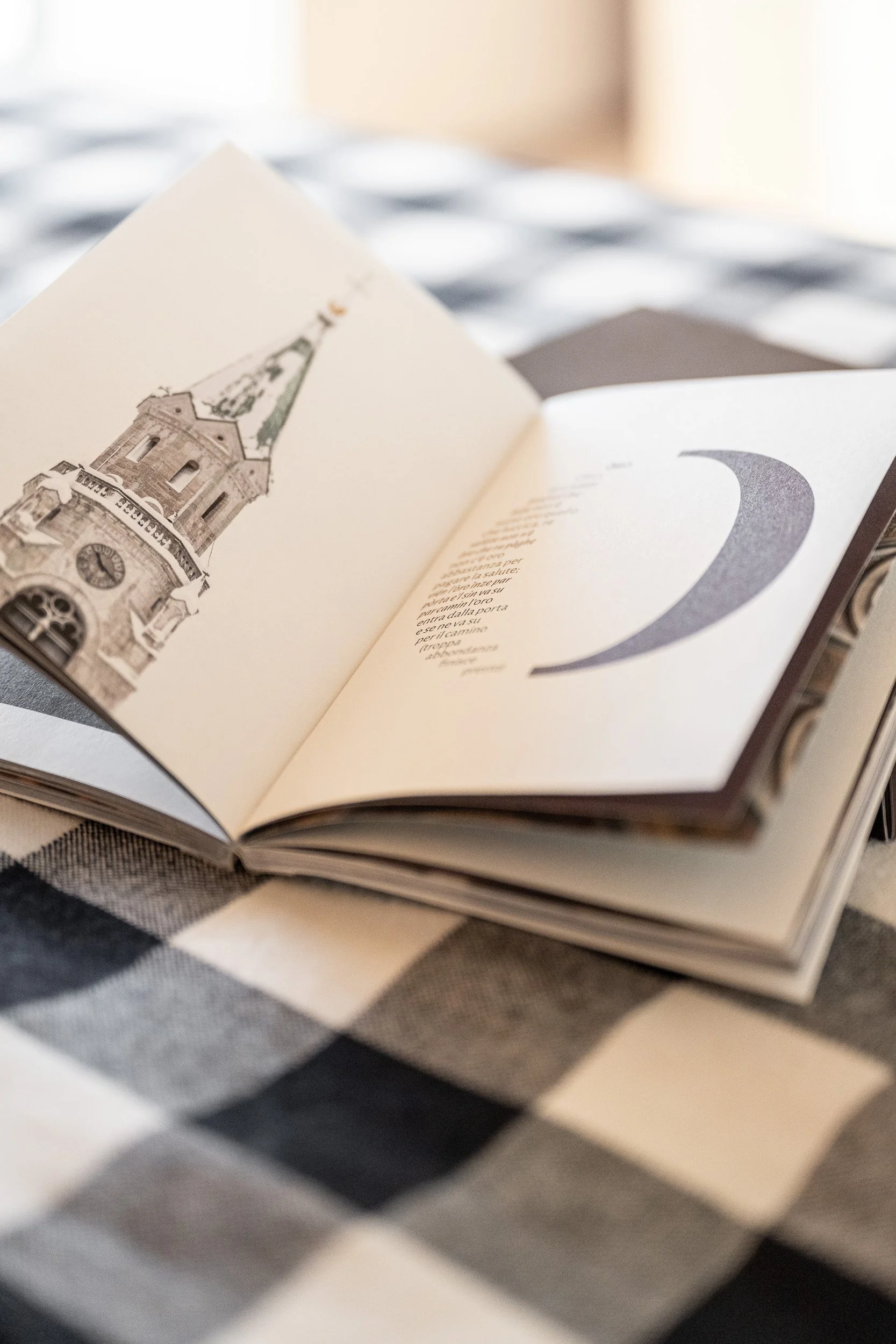 Libro aperto alla luce del mattino, sullo sfondo di una tovaglia a quadri, al momento della colazione. Piacevoli letture mattutine.