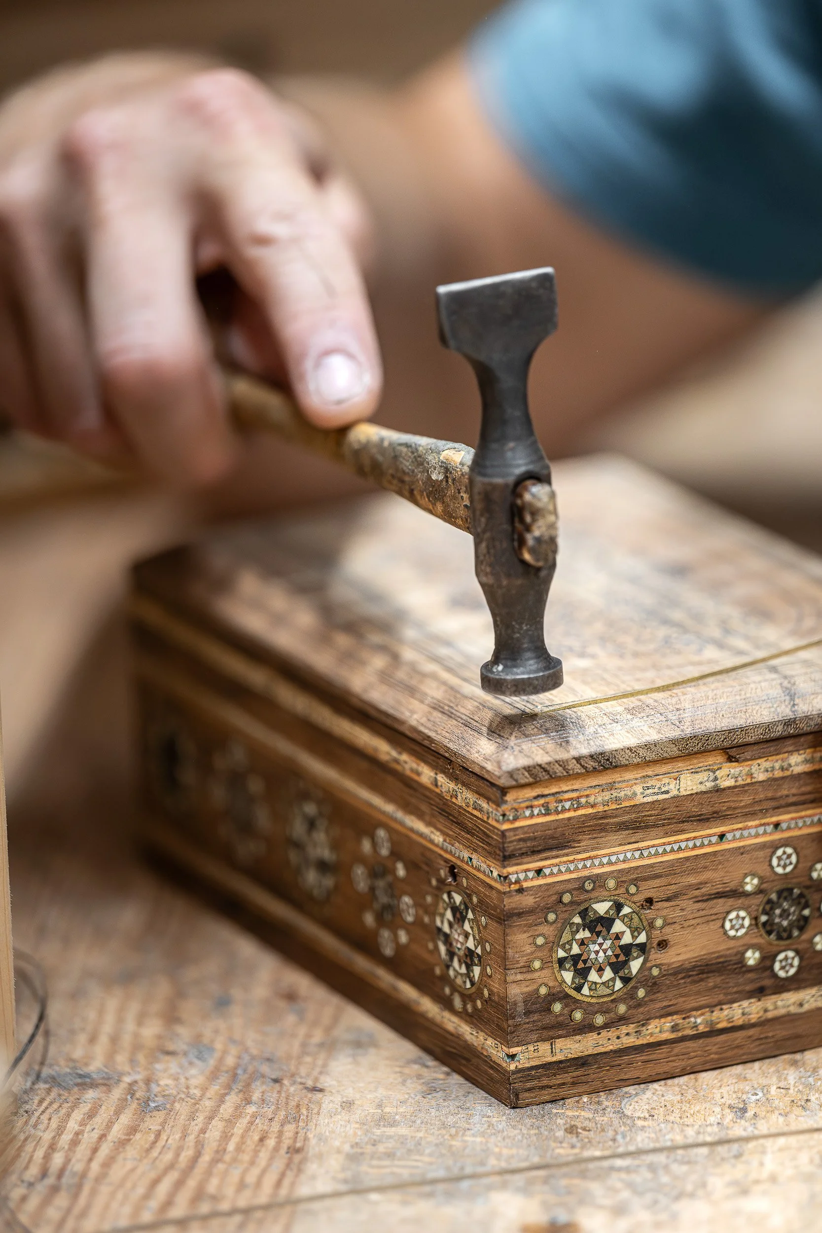 L’artigiano appollaiato su di un alto sgabello, ferisce il rosso palissandro delle Indie con incisioni ora geometriche, ora dolci, ora arrovellate, come solo la bizzarra fantasia araba saprebbe concepire. È il Tar-kashi  arte antica.