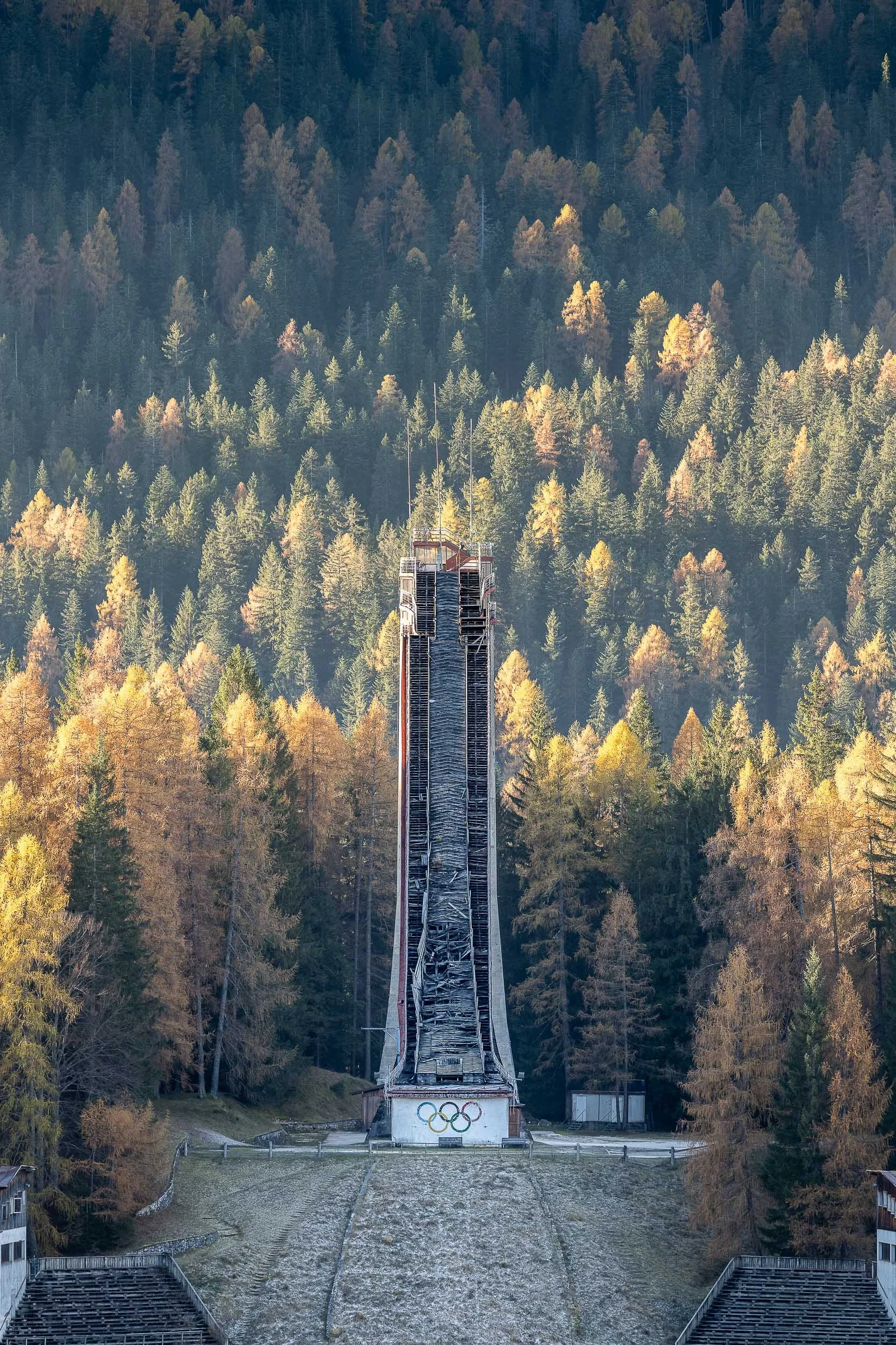 Una torre di salto con un fondale di un'enorme foresta di alberi autunnali. Si vede anche un’area di parcheggio e le strutture di supporto.