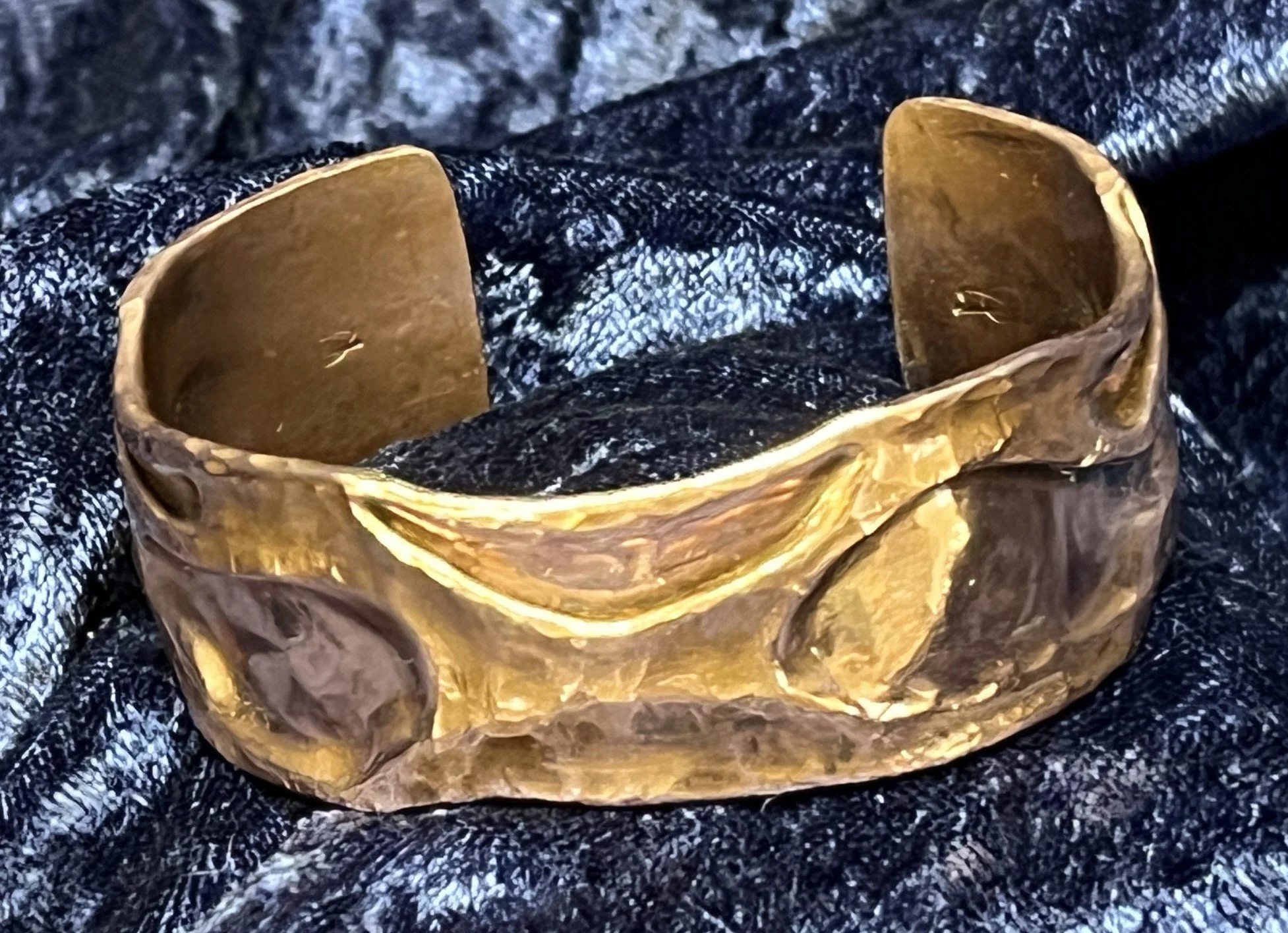 Copper bracelet laying on a blue background.