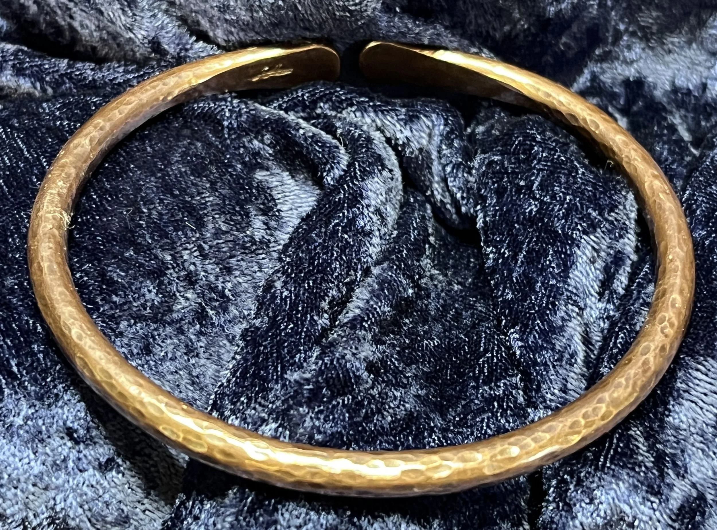 Copper bracelet laying on a blue background.