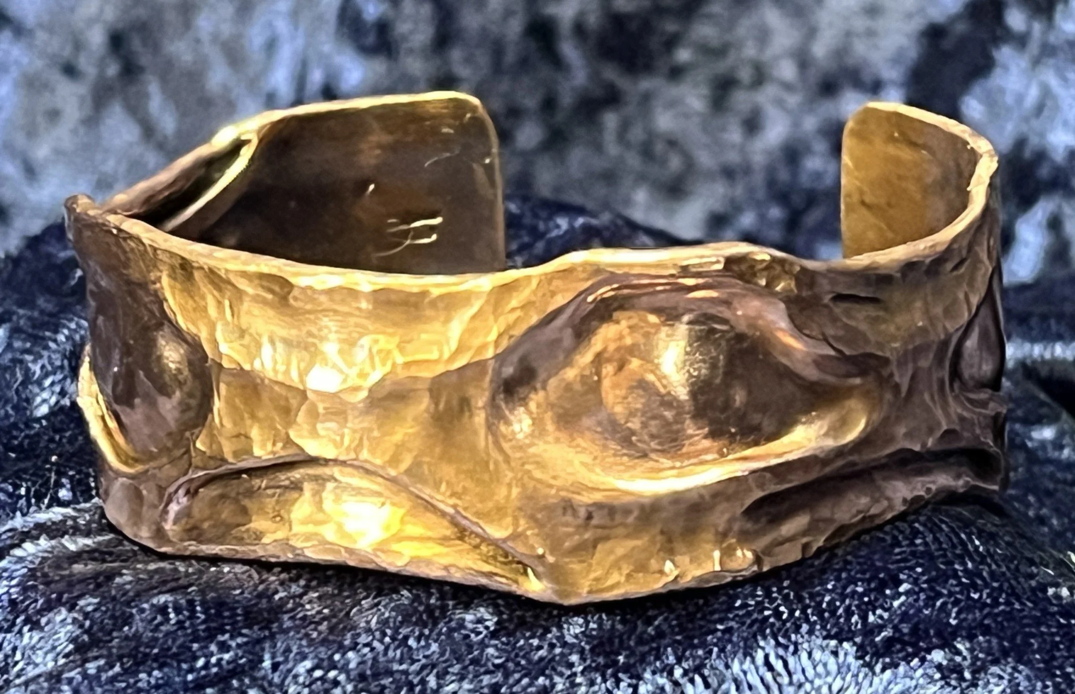 Copper bracelet laying on a blue background.