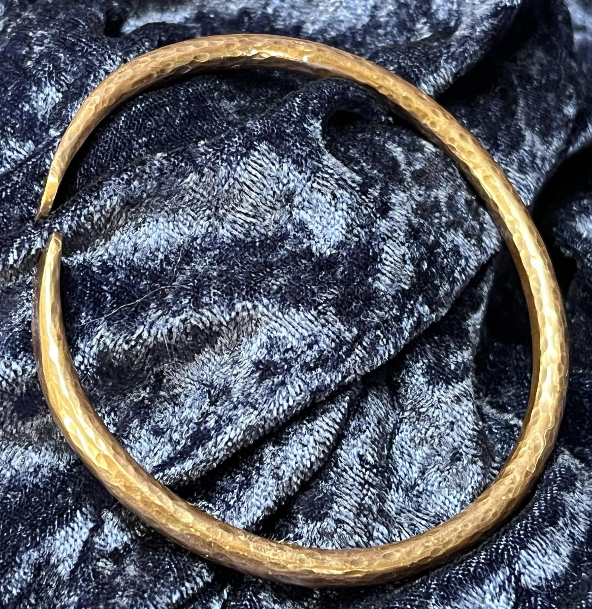 Copper bracelet laying on a blue background.