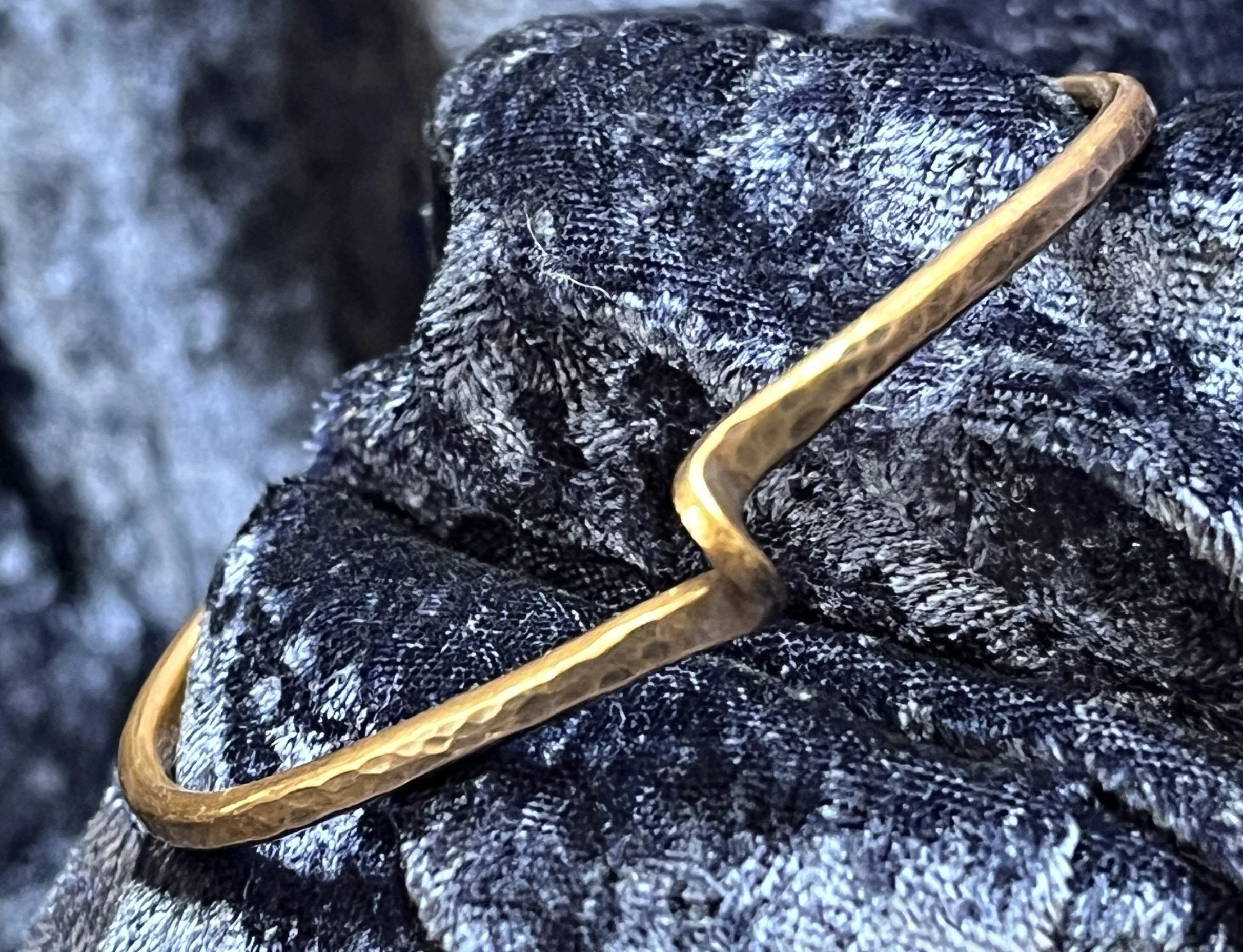 Hand-Forged Copper Twist Cuff Bracelet on blue background