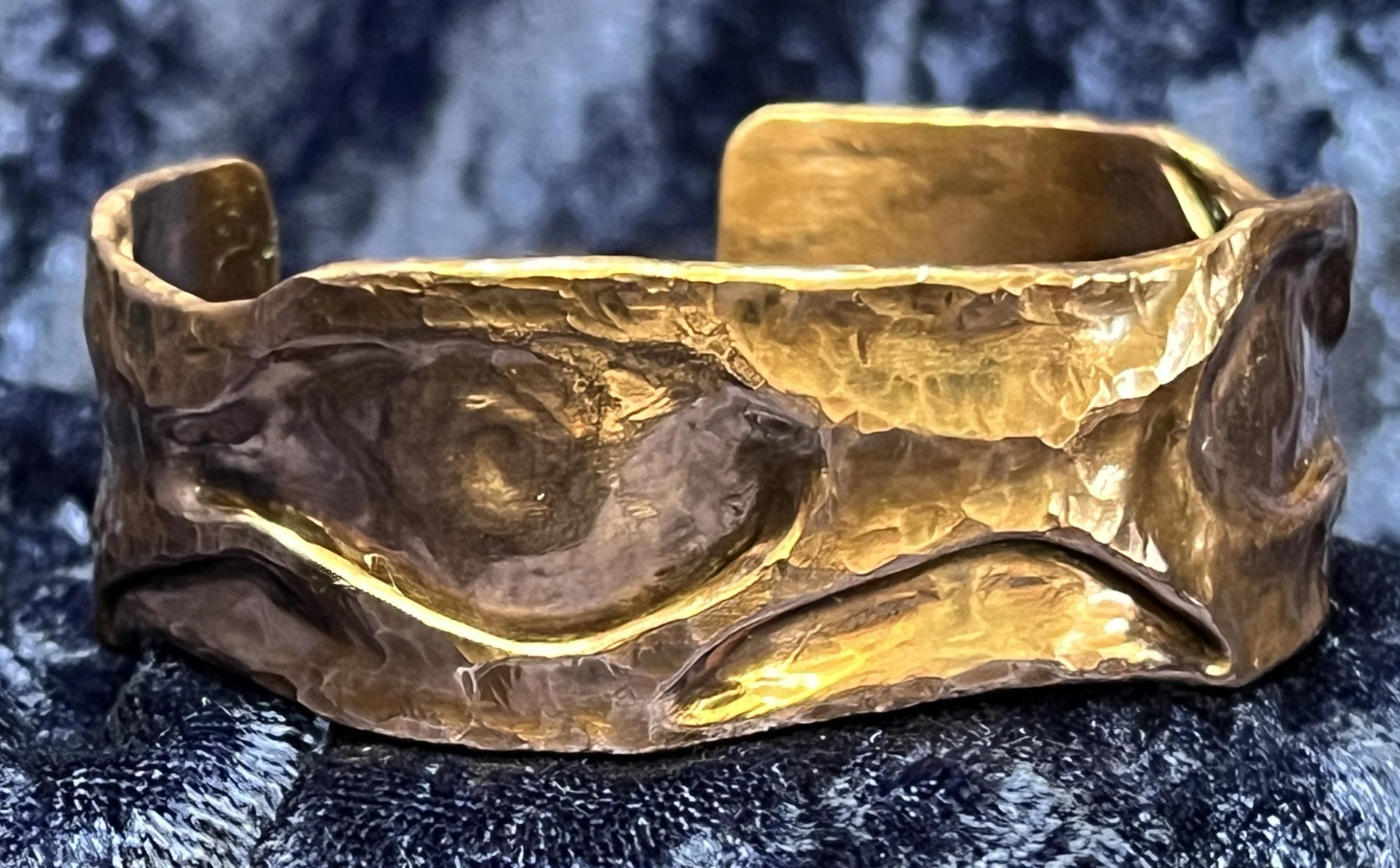 Copper bracelet laying on a blue background.
