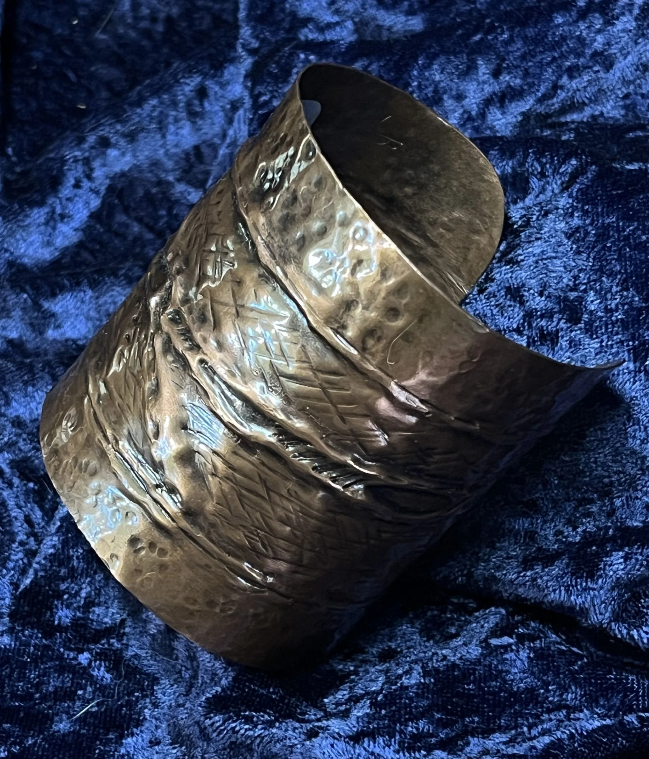 Copper bracelet laying on a blue background.