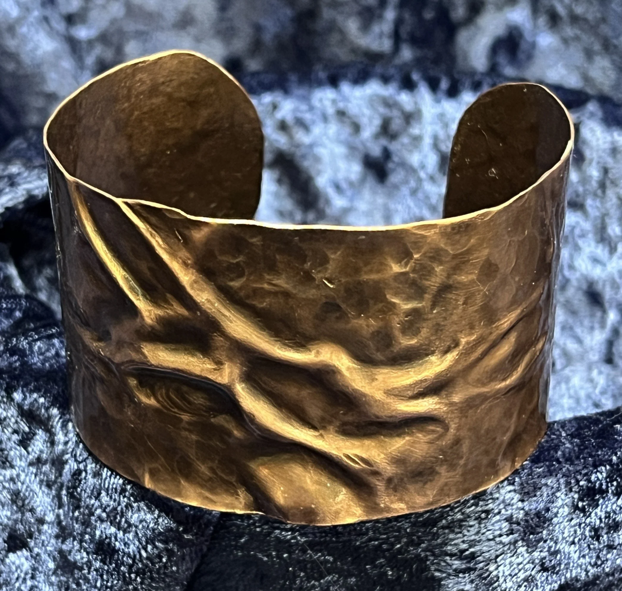 Copper bracelet laying on a blue background.