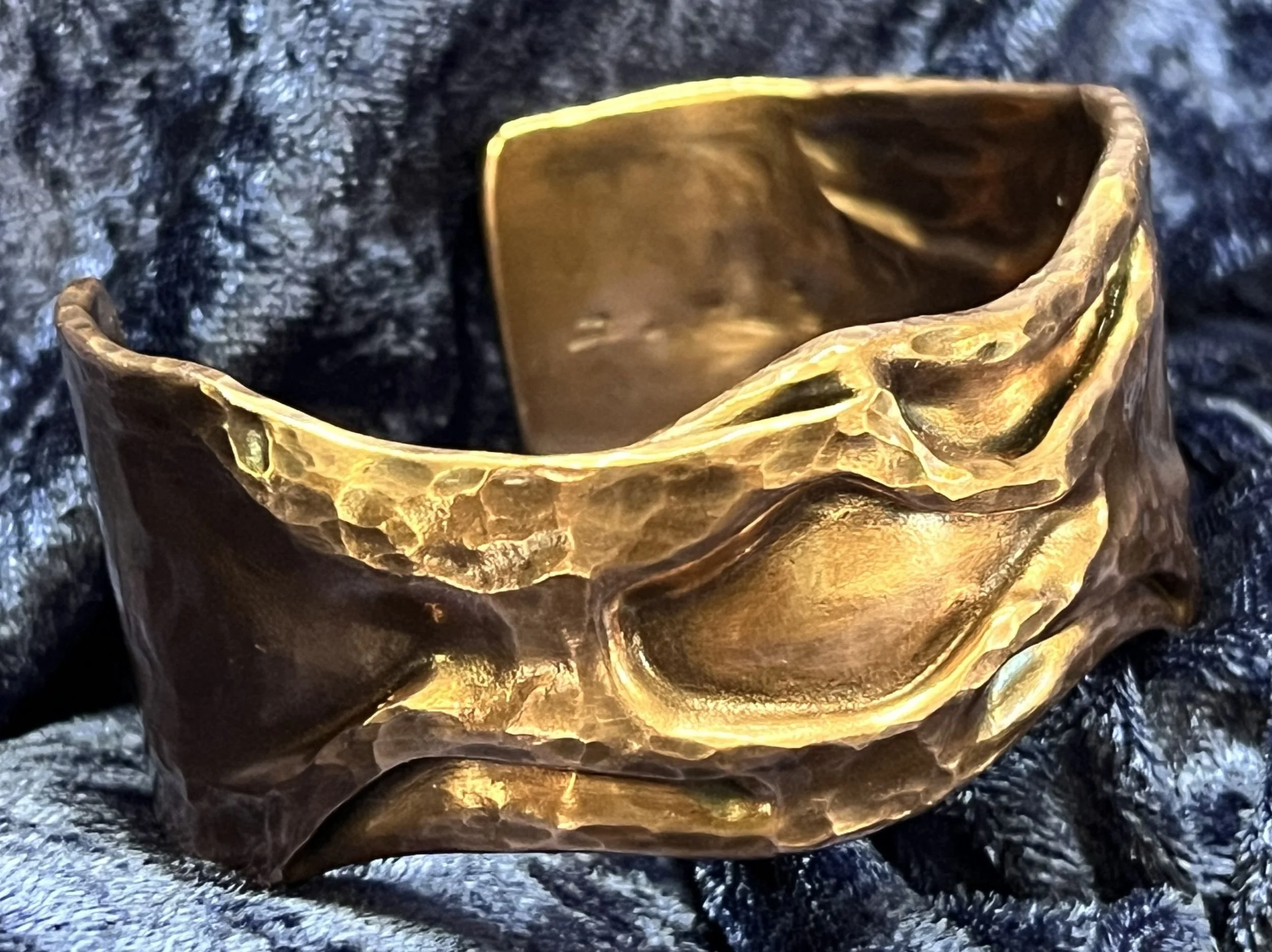 Copper bracelet laying on a blue background.