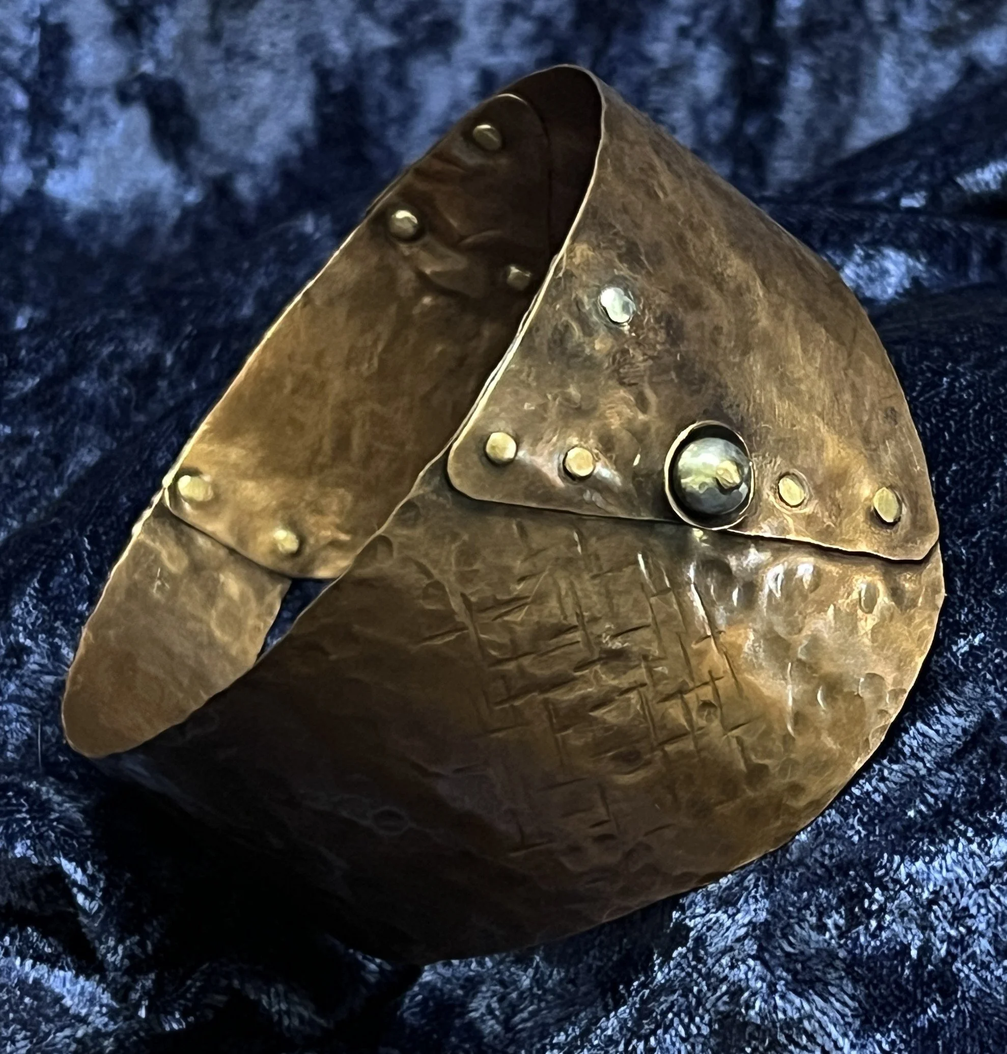 Copper bracelet laying on a blue background.