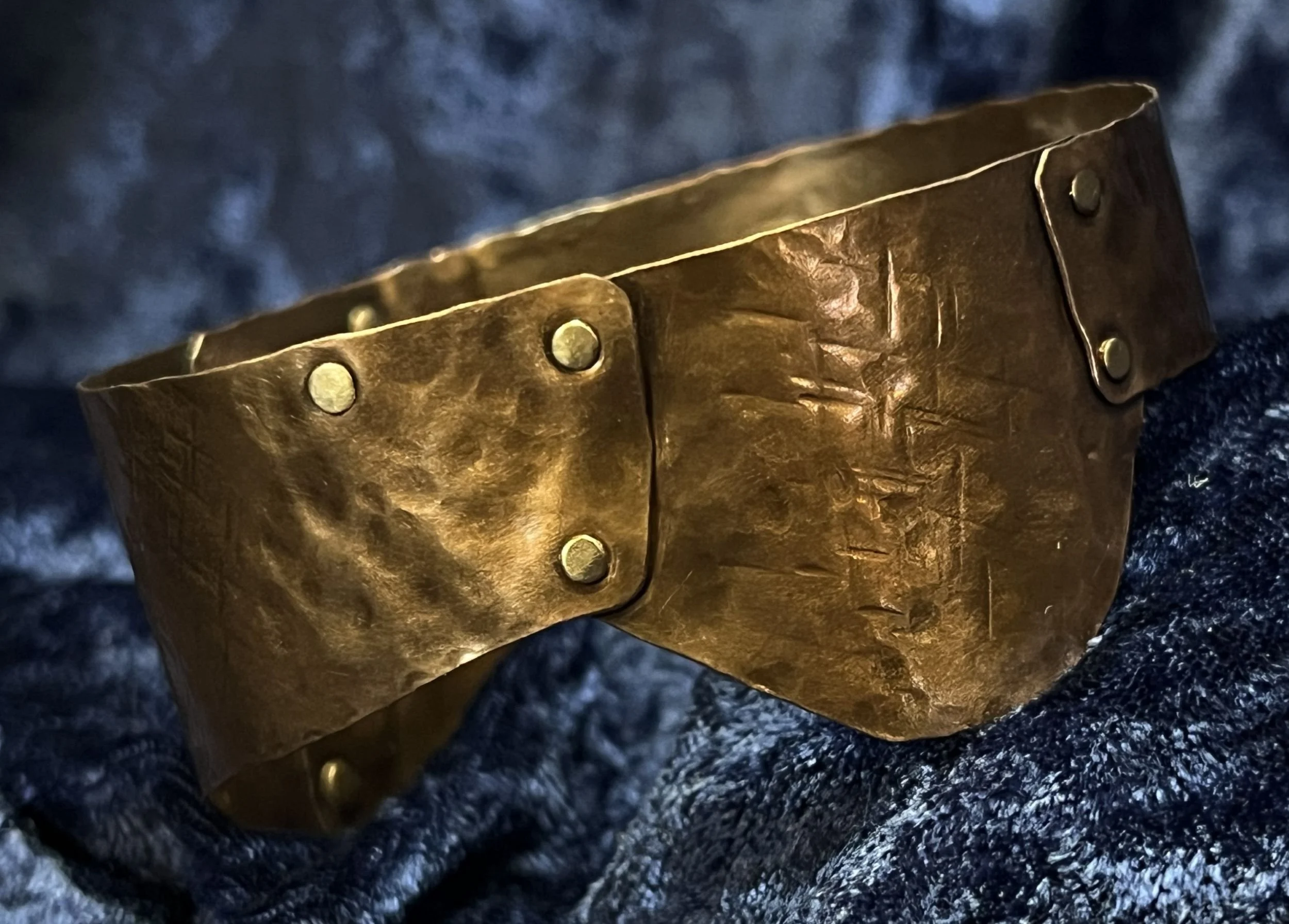 Copper bracelet laying on a blue background.