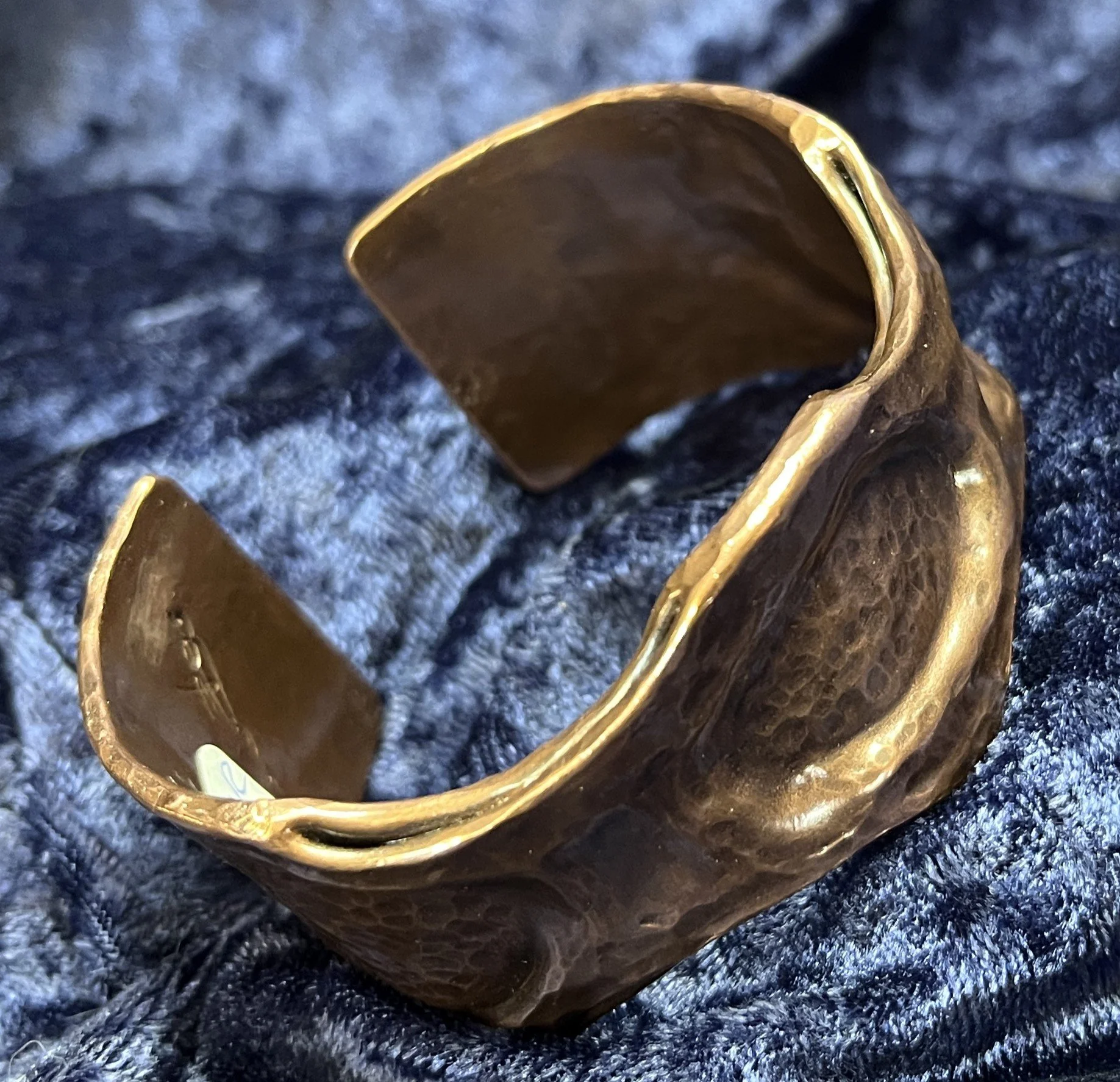 Copper bracelet laying on a blue background.