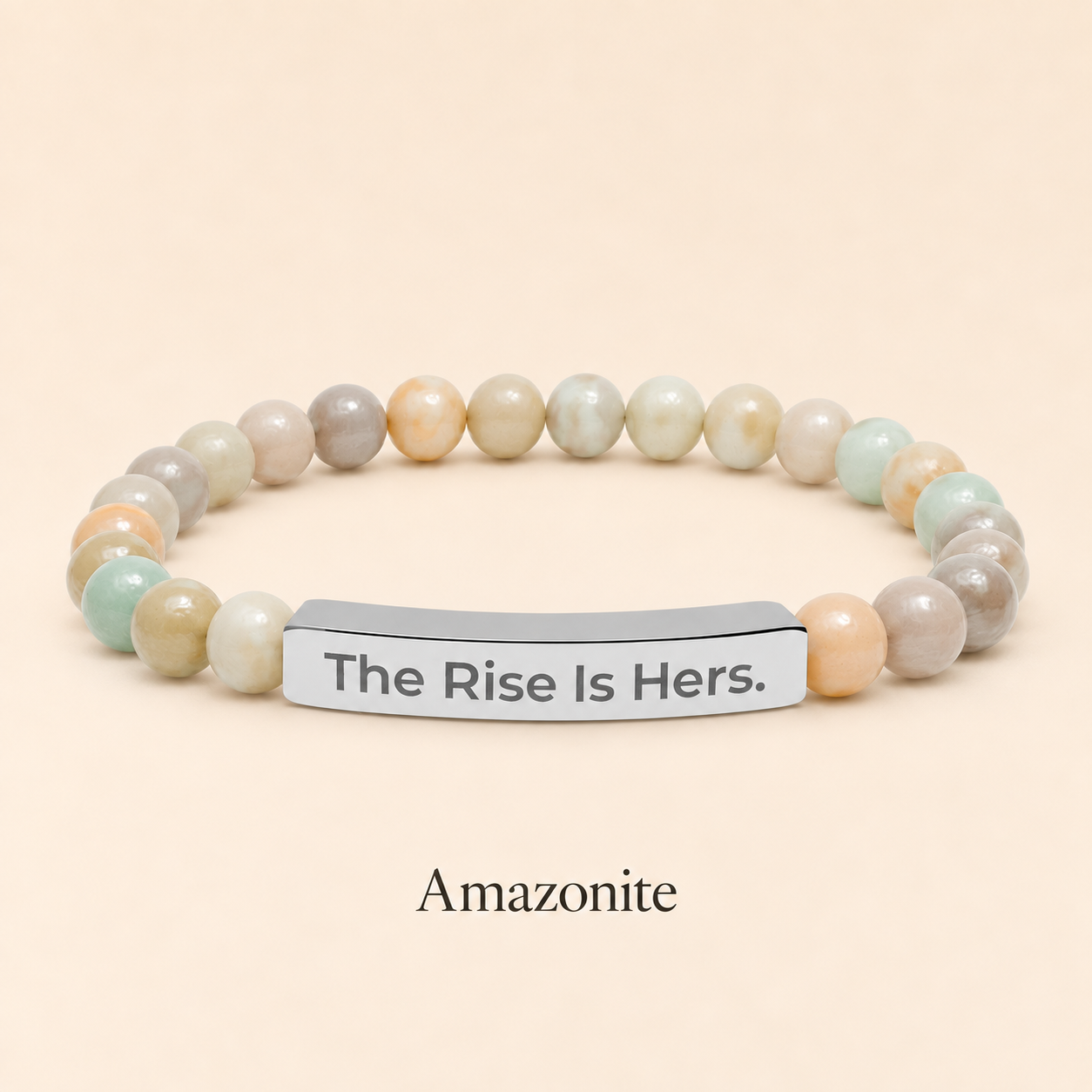 Amazonite beaded stretch bracelet with a silver-tone bar engraved with The Rise Is Hers, displayed on an ivory background.
