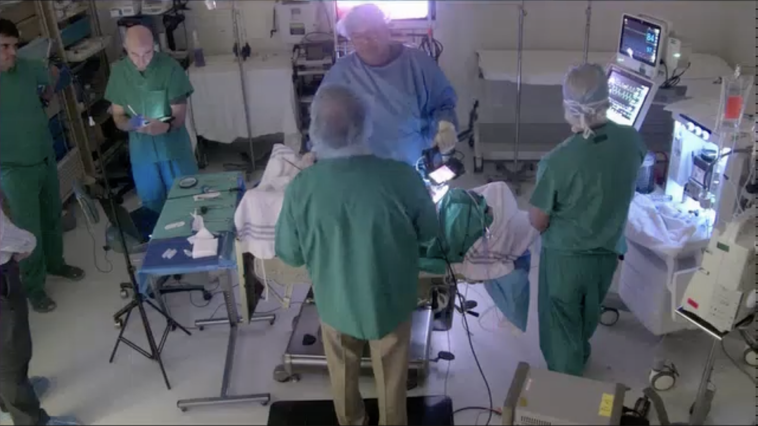 Hospital operating room with medical staff and patient undergoing surgery.
