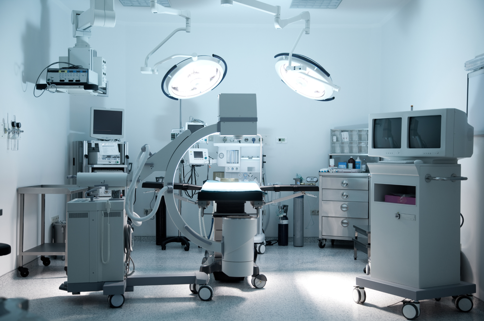 Empty operating room with surgical lights, medical monitors, and medical equipment, ready for surgery.