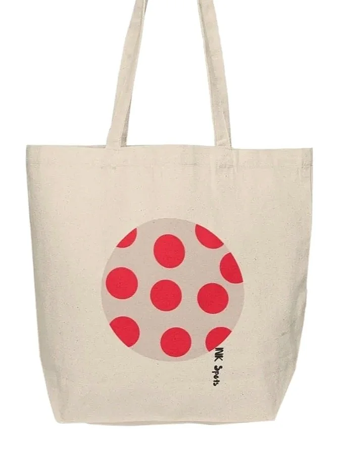 A beige tote bag with red polka dots in a circle pattern. The bag has two handles.