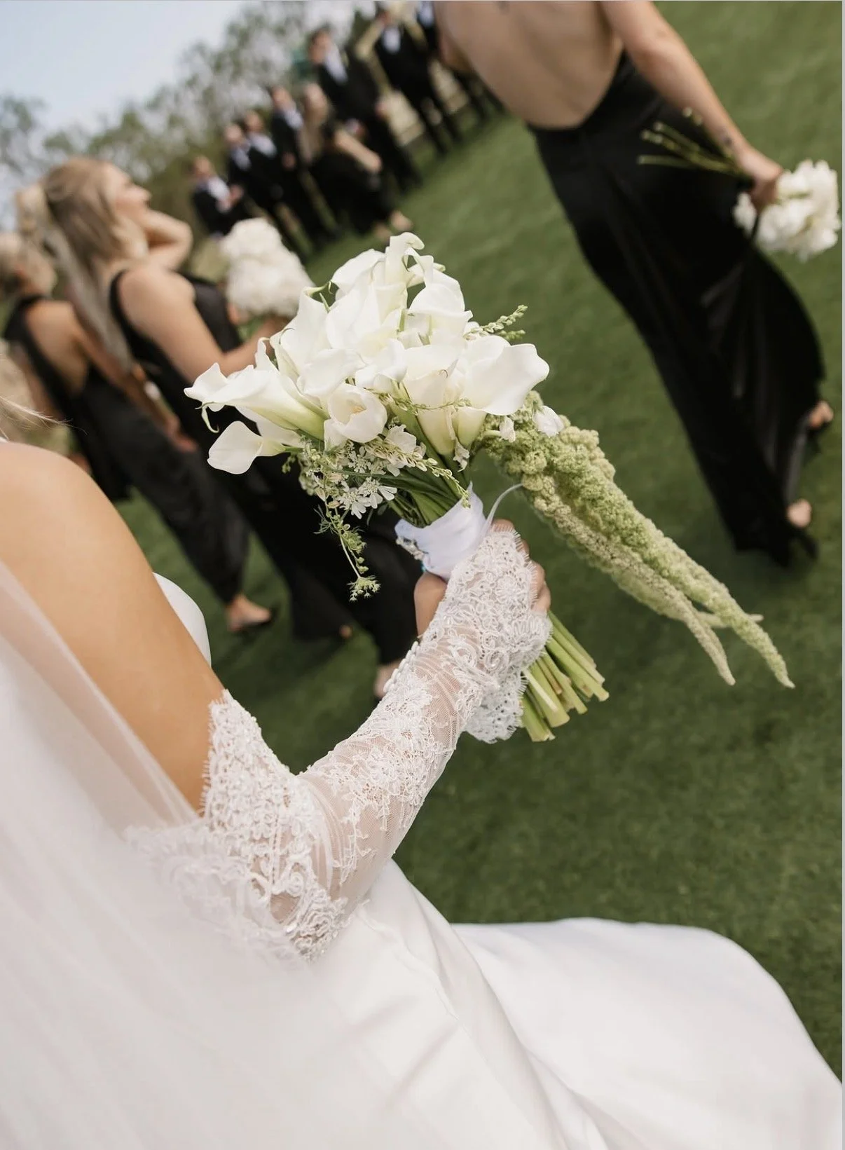 Bride holding a bouquet of white flowers during a wedding ceremony outdoors