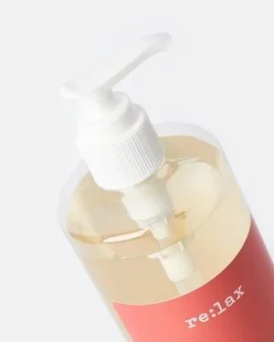 A clear bottle containing a re:lax skincare product with a white pump and a red label.
