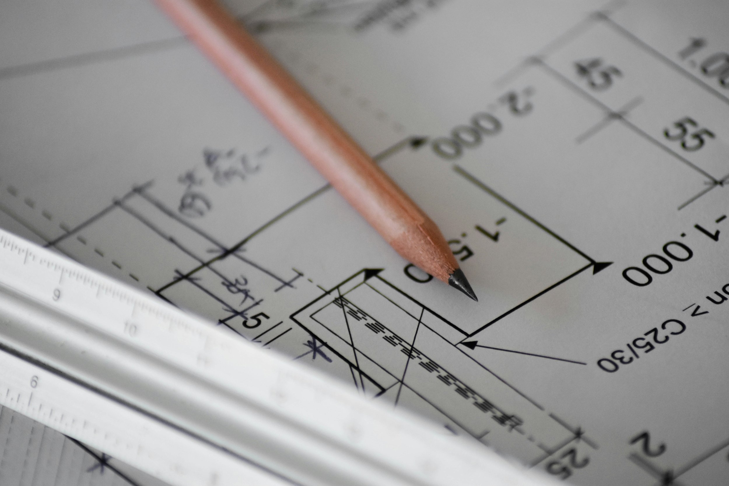 Close-up of a technical drawing or blueprint with a mechanical pencil resting on it, showing measurements and diagrams.