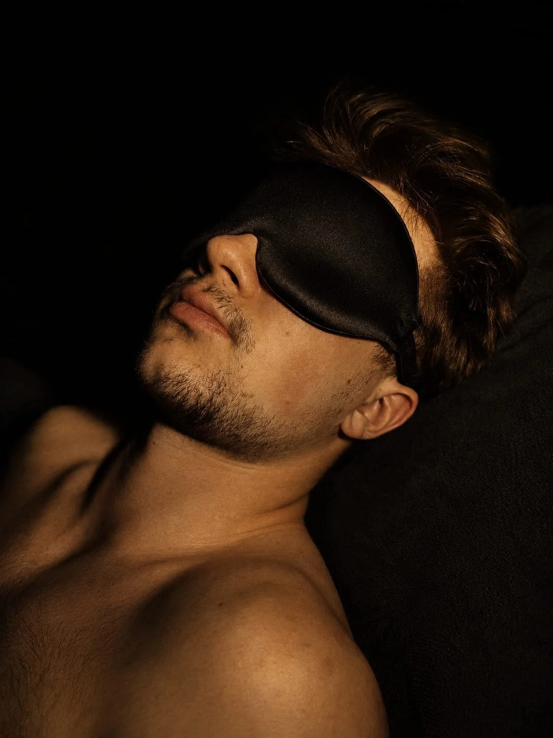 A man wearing a black blindfold during a private sensory experience. Silence, darkness and touch create an atmosphere of deep relaxation and inner calm.