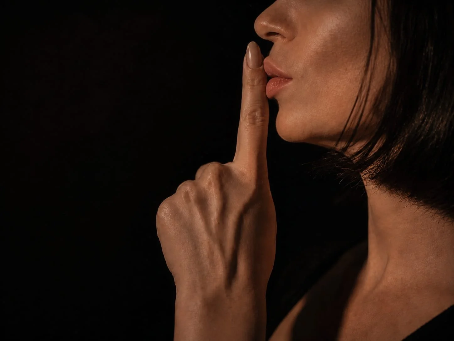 Eine Frau fordert mit dem Finger an den Lippen zur Stille auf und symbolisiert die ruhige Atmosphäre eines privaten sensorischen Erlebnisses für Männer in Zürich.