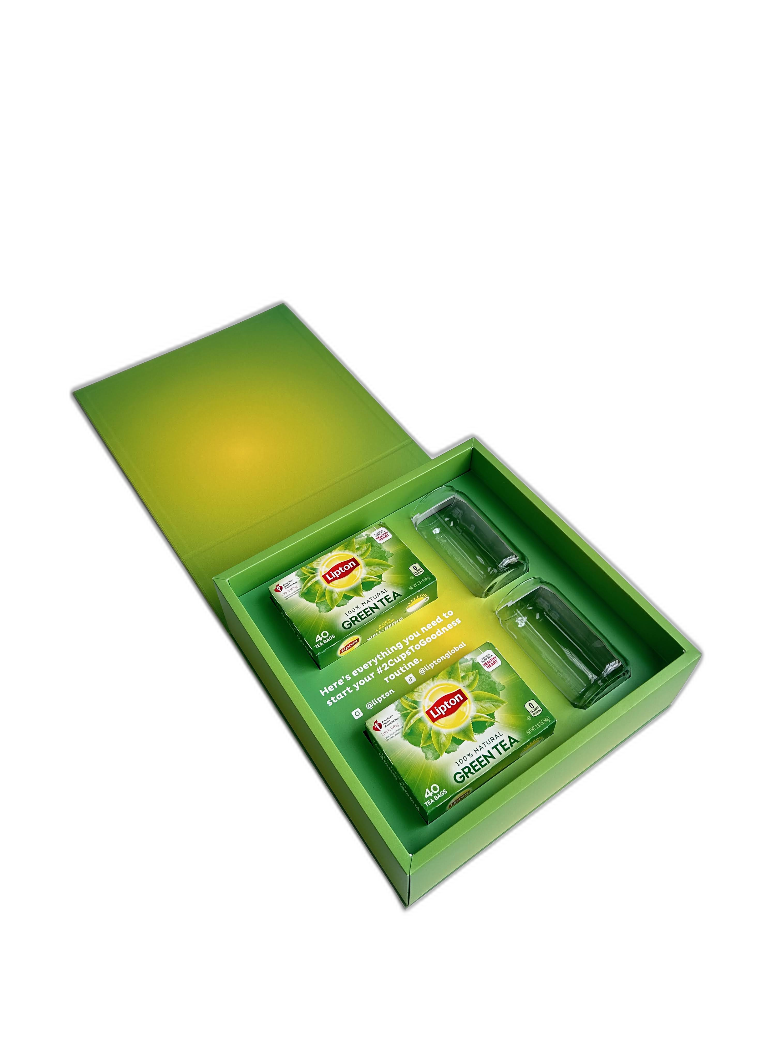Open green box containing Lipton organic green tea boxes and empty glass cups.