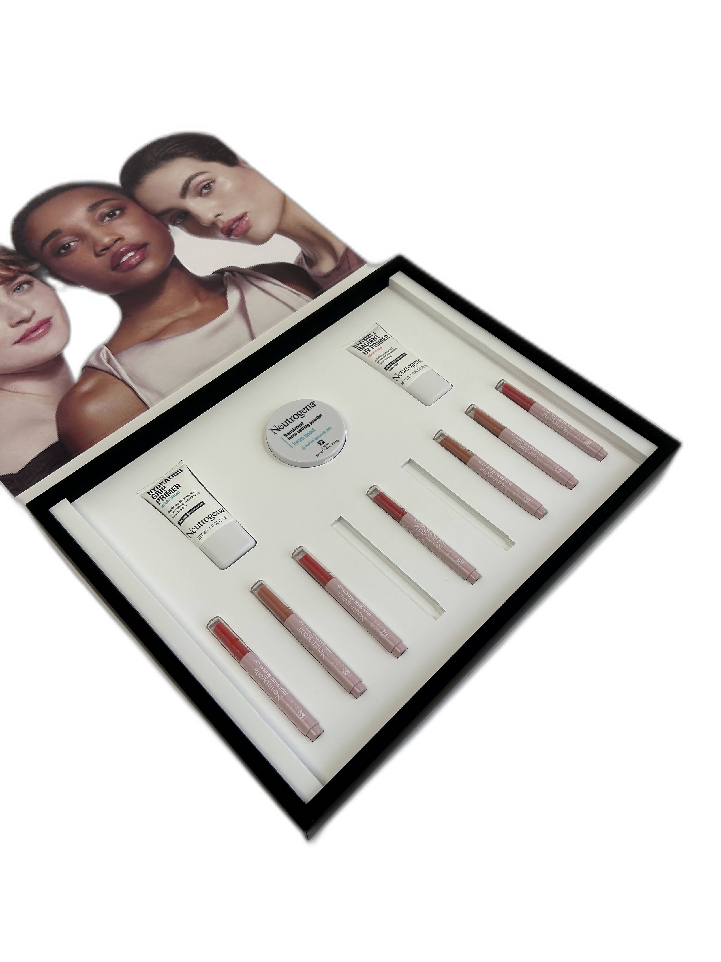 Beauty products including Neutrogena Hydro Boost water gel, lip glosses, and other skincare items displayed in a white tray, with a photograph of three women with diverse skin tones and makeup looks in the background.