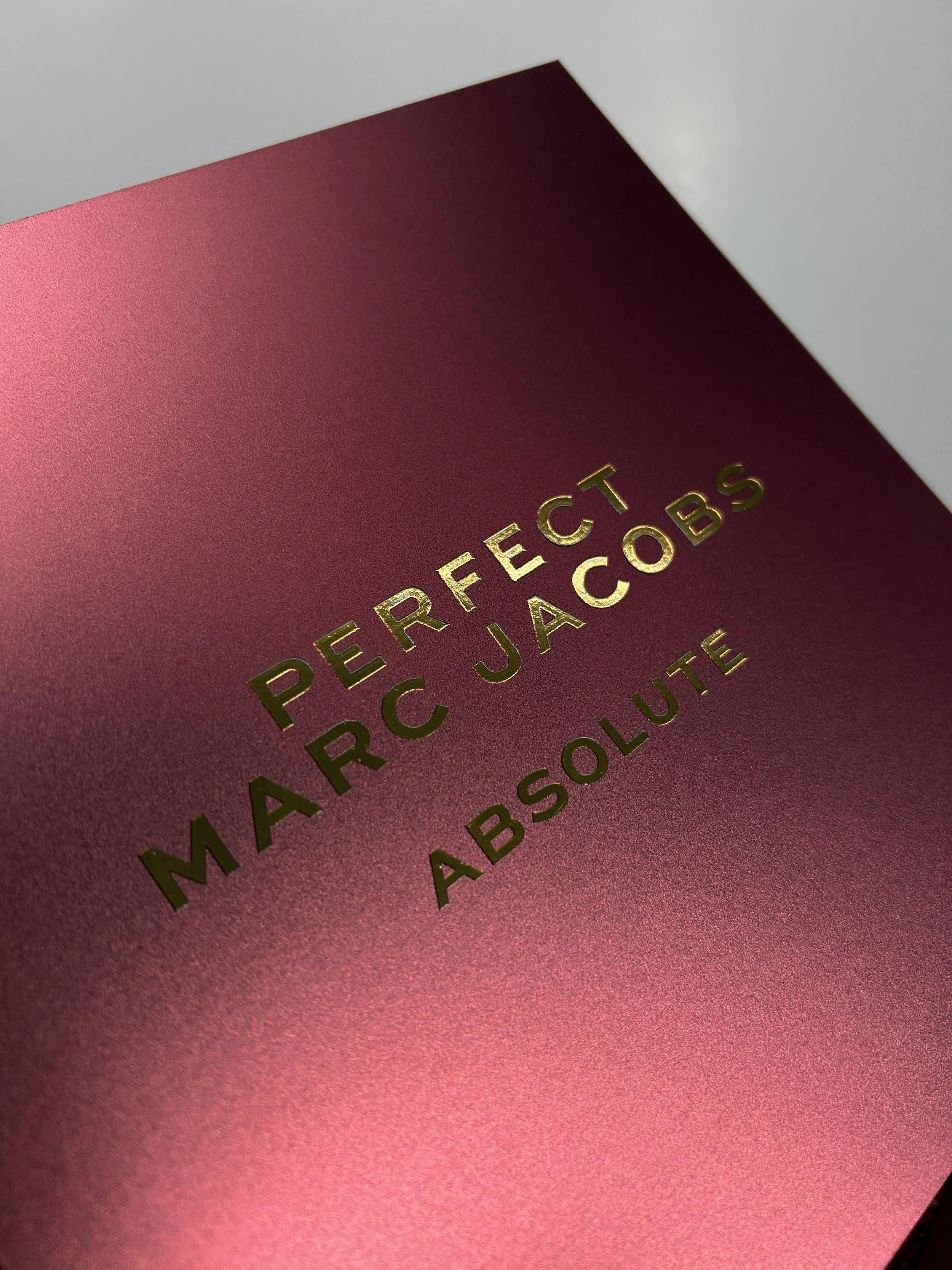 Close-up of a red book or box with gold embossed text that reads "PERFECT ARC ABSOLUTE".