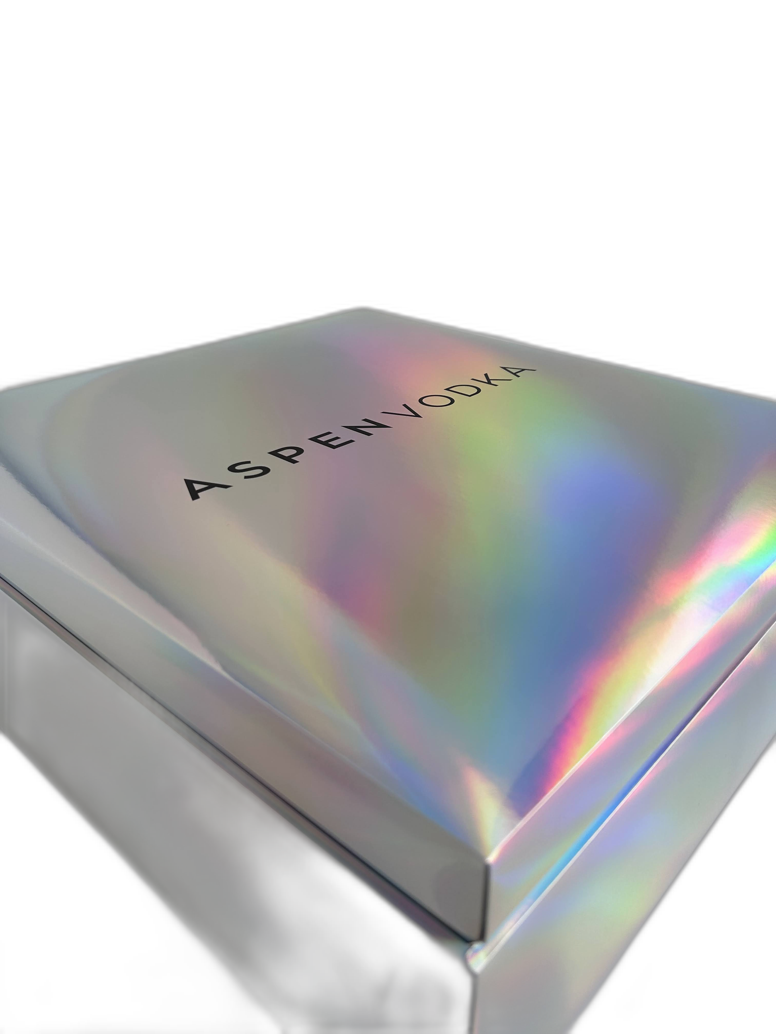 A box with a holographic surface displaying the word 'ASPENVOOKA' in black letters.