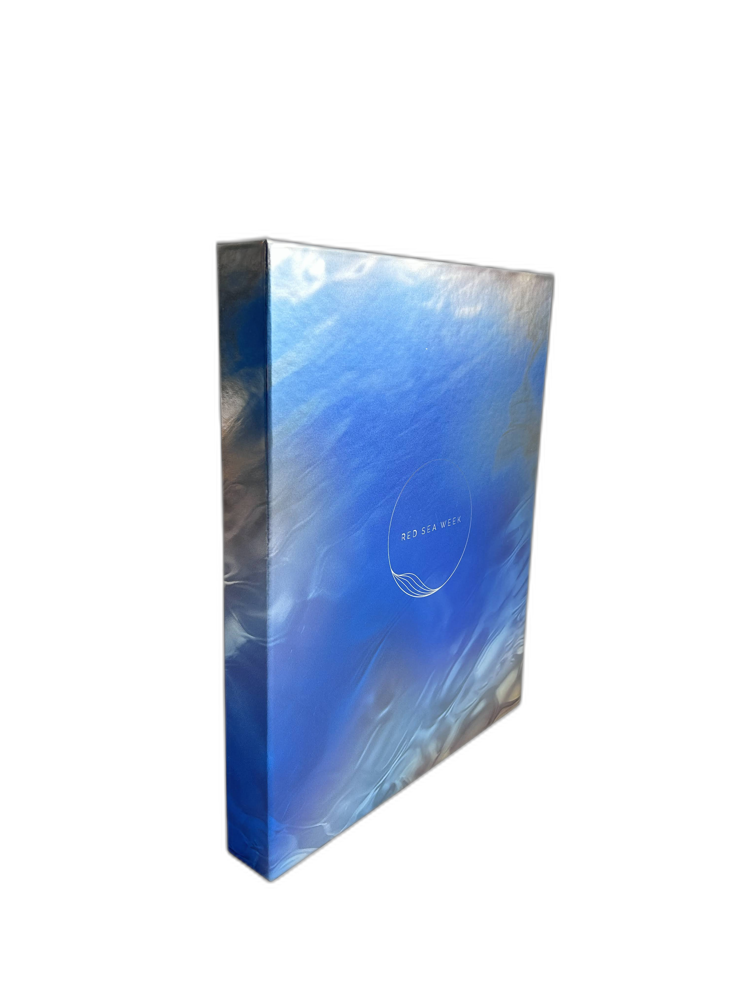 A rectangular box with a shiny metallic surface reflecting blue sky and clouds, labeled 'RED SEA WEEK'.