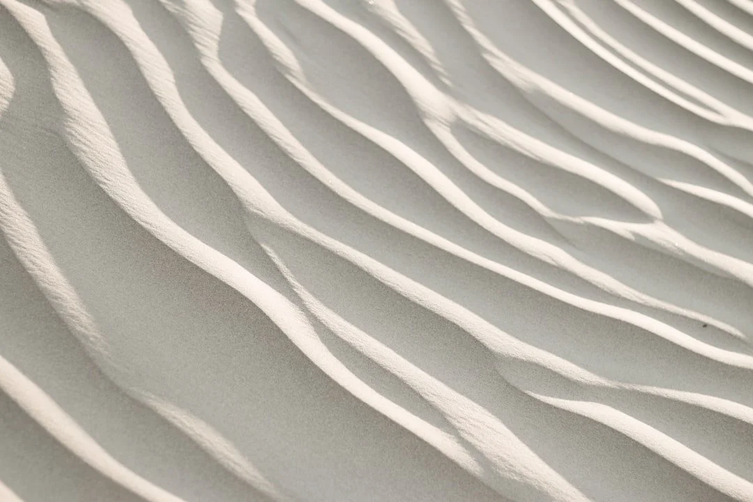 Weißer Sand mit wellenförmigen Mustern, geschaffen durch Wind.