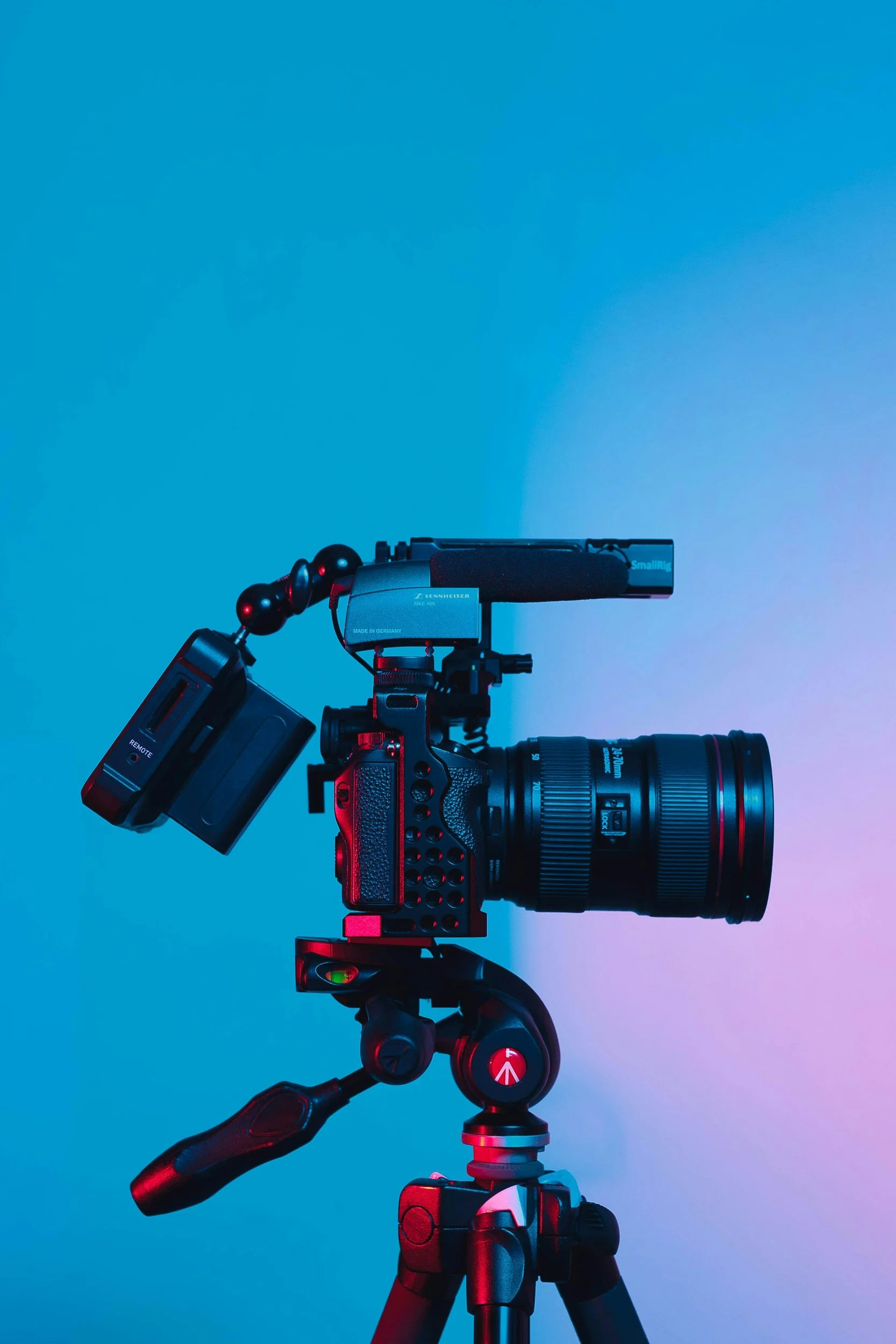 Nahaufnahme einer professionellen Filmkamera auf einem Stativ vor blauer Hintergrund.