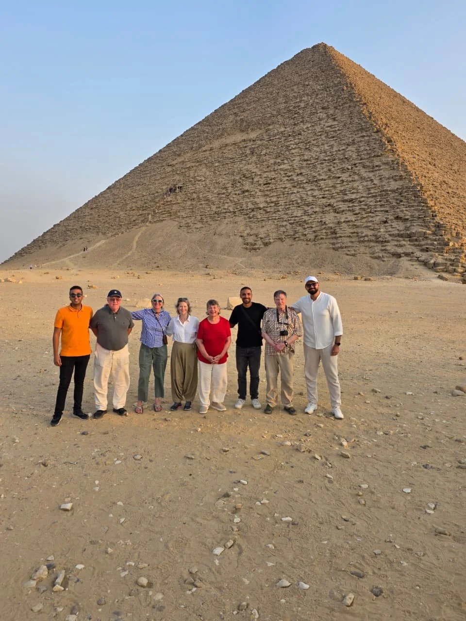 A small group of travelers standing at the base of the Red Pyramid in Dahshur, Egypt, during the Egypt Uncharted November 2025 journey.