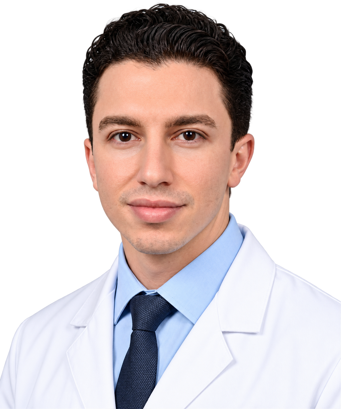 A young man with dark, curly hair, wearing a white medical coat, a light blue shirt, and a dark tie, looking directly at the camera with a slight smile.