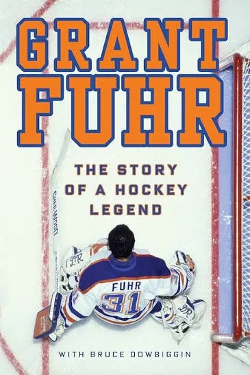 Book cover titled 'Grant Fuhr: The Story of a Hockey Legend' featuring a hockey goalie sitting on the ice, wearing a uniform with 'Fuhr' and the number 31, and a hockey net on the right.