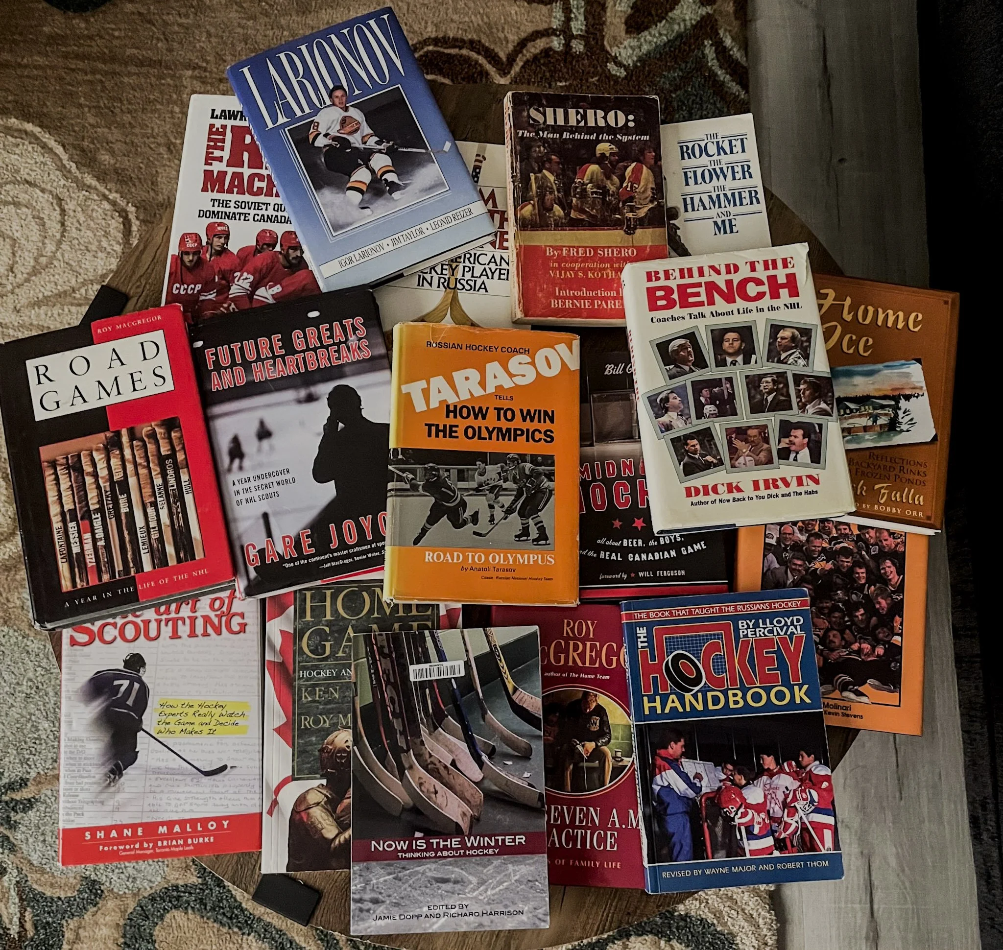A collection of hockey books arranged on a table, including titles about hockey history, coaching, and personal stories.