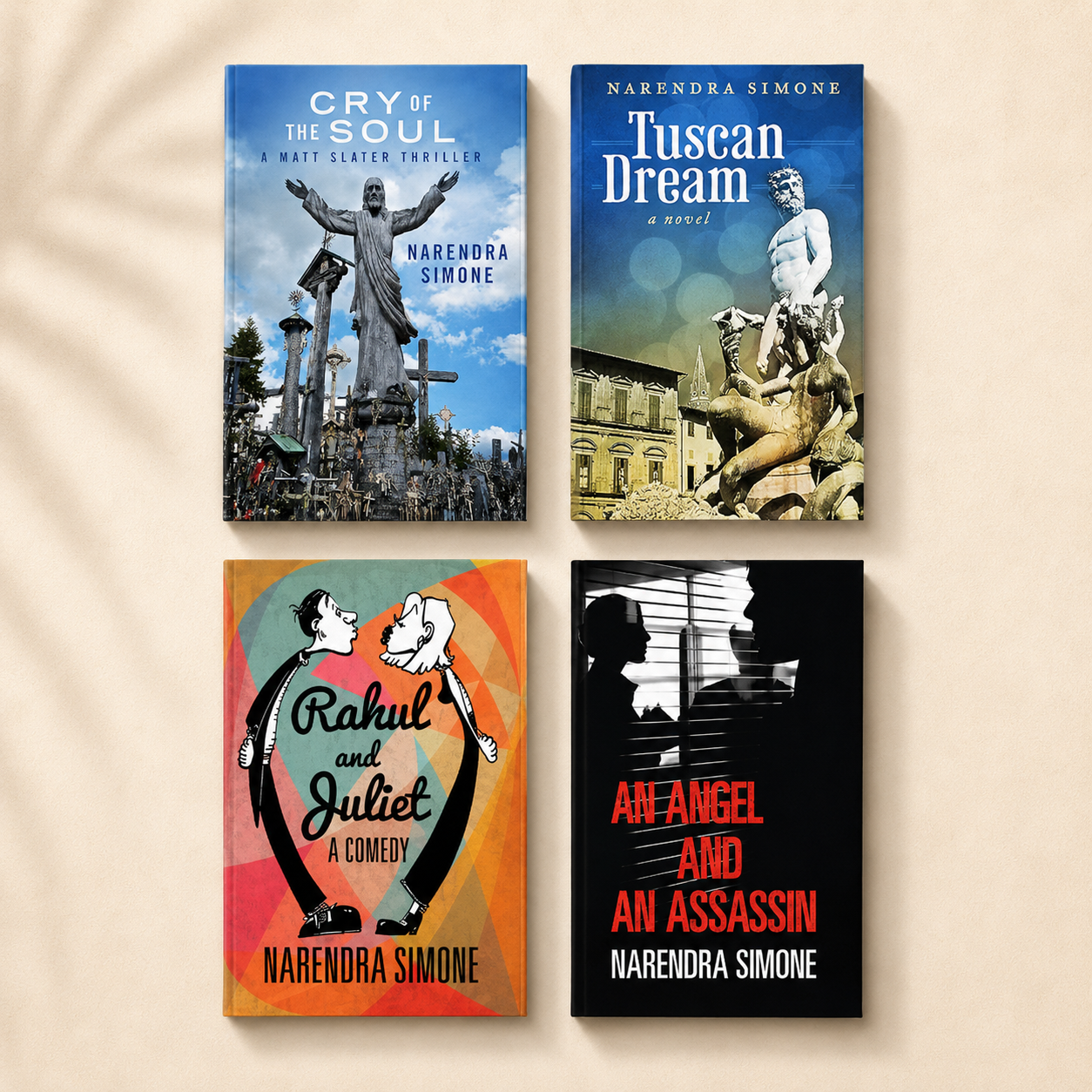 Four books by Narendra Simone arranged on a beige surface. The top left book titled 'Cry of the Soul' features a statue of Jesus on a cross with a blue sky background. The top right book titled 'Tuscan Dream' shows a classical sculpture in front of yellow buildings. The bottom left book titled 'Rahul and Juliet' has an illustrated cover with two characters holding hands. The bottom right book titled 'An Angel and An Assassin' has a black and white photo of two people with blinds, with red and white text.