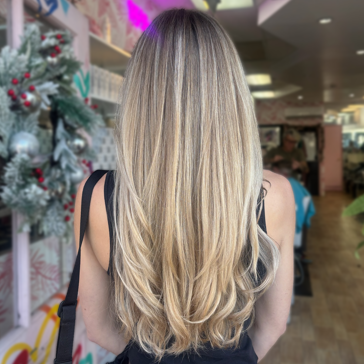 Back of woman with long, wavy blonde hair in a store decorated for Christmas.
