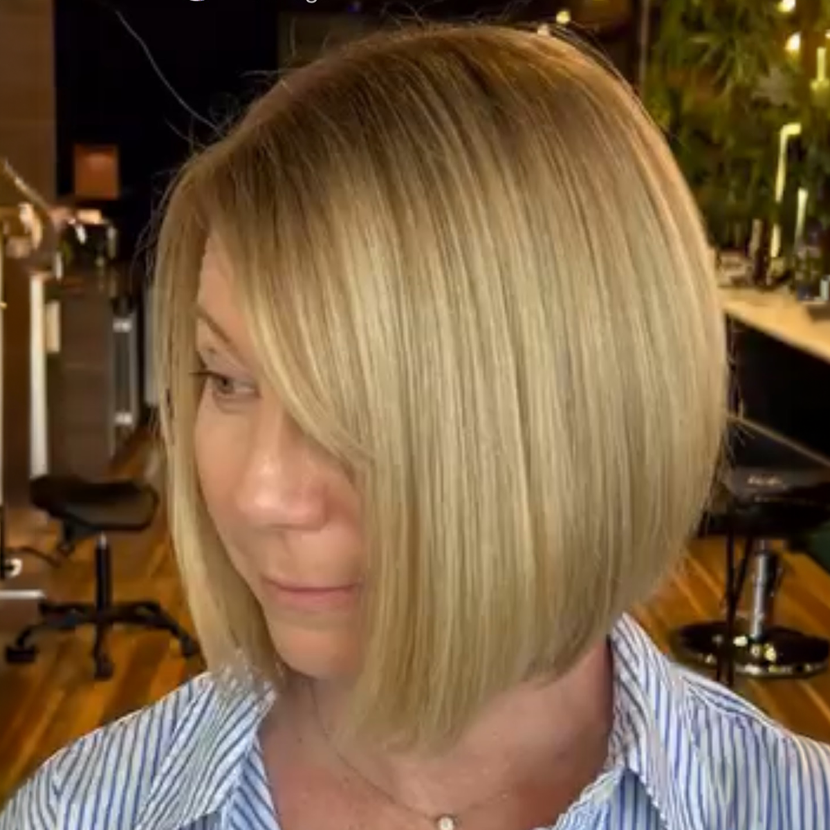 Woman with blonde, straight, layered bob haircut in a hair salon.