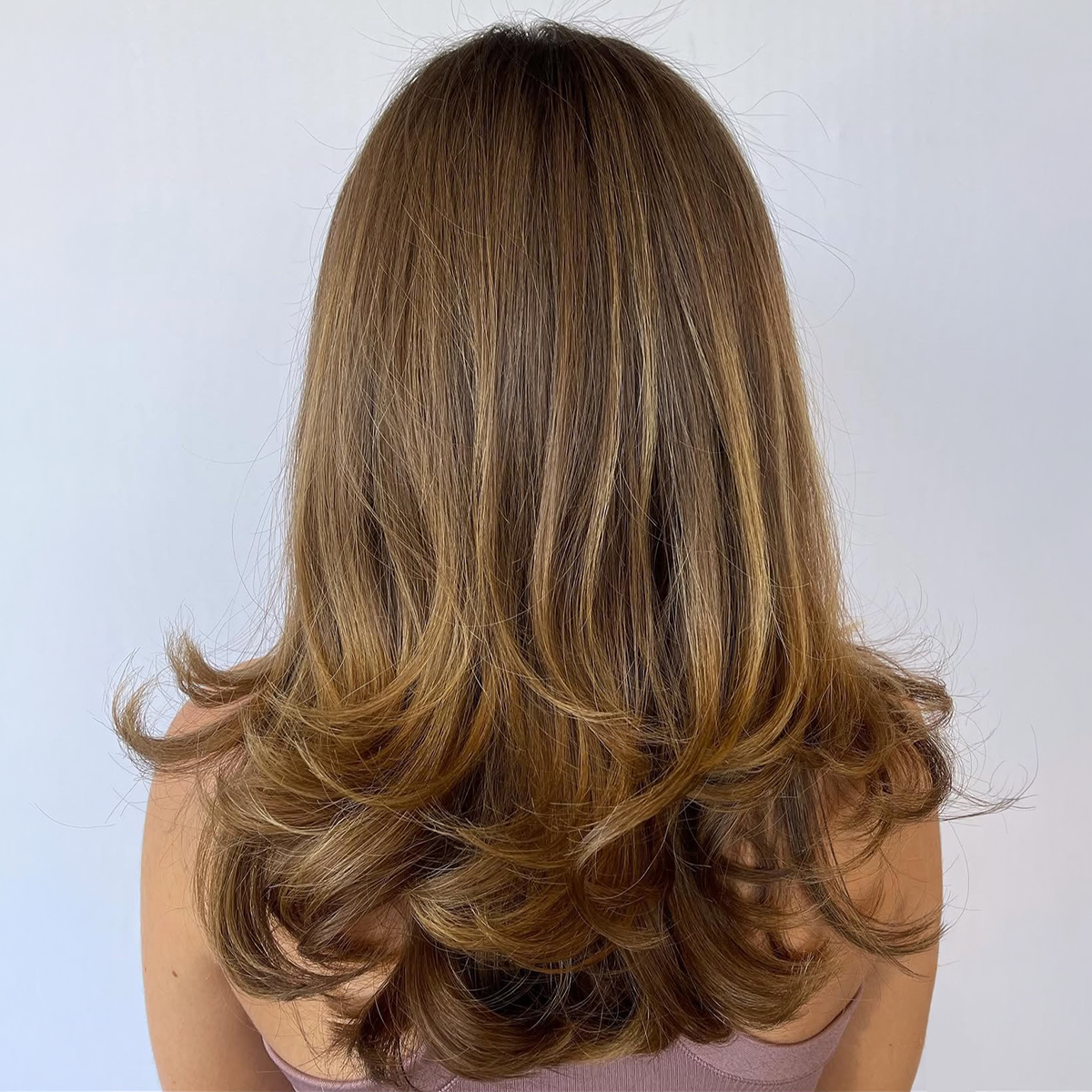 Back view of a woman with shoulder-length, wavy, light brown hair.