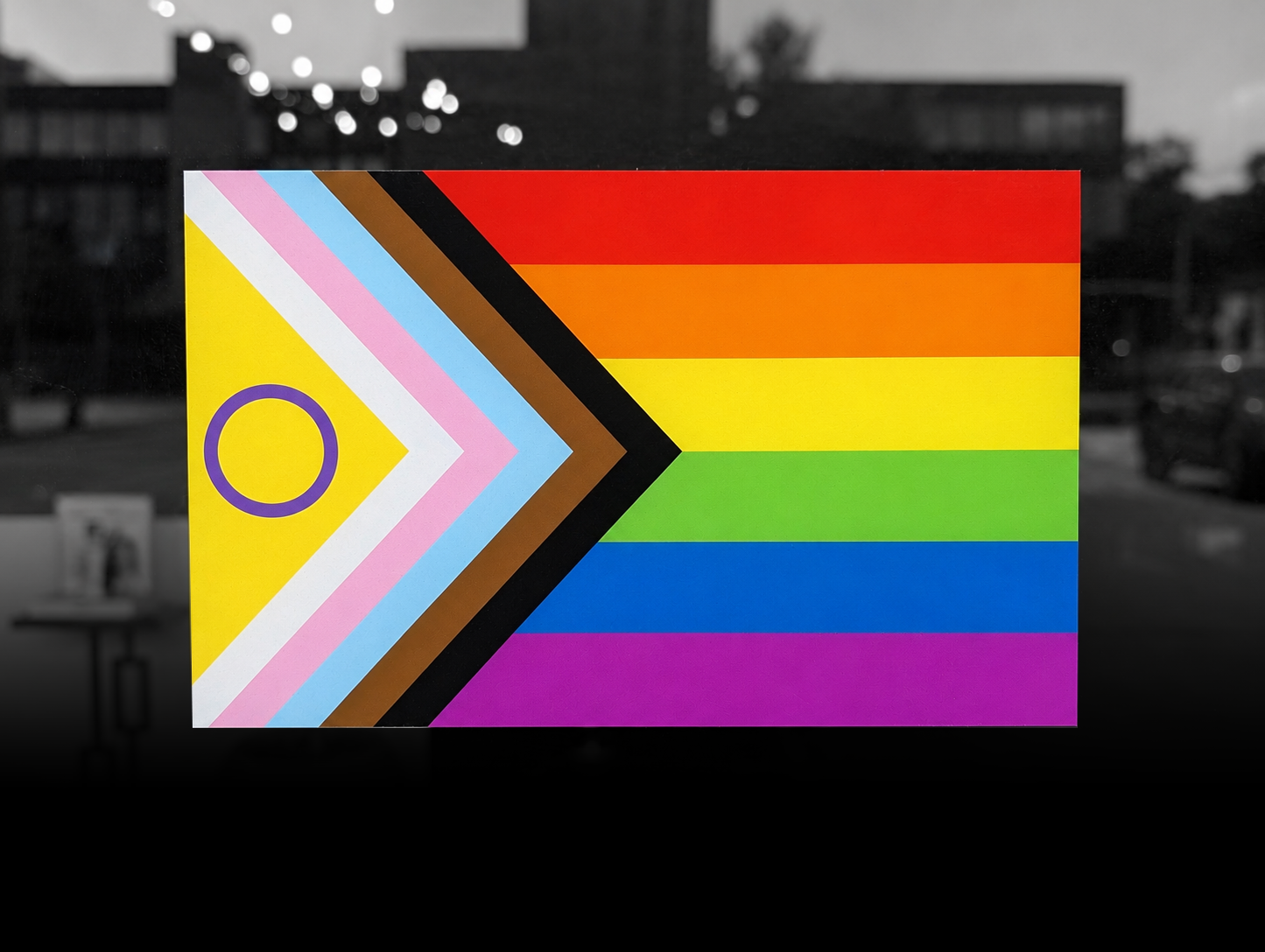 A display featuring a rainbow pride flag with horizontal stripes in red, orange, yellow, green, blue, and purple, alongside a chevron pattern with colors pink, white, light blue, brown, black, and a purple circle on a yellow background.