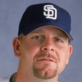 Portrait of a man wearing a San Diego Padres baseball cap against a plain background.
