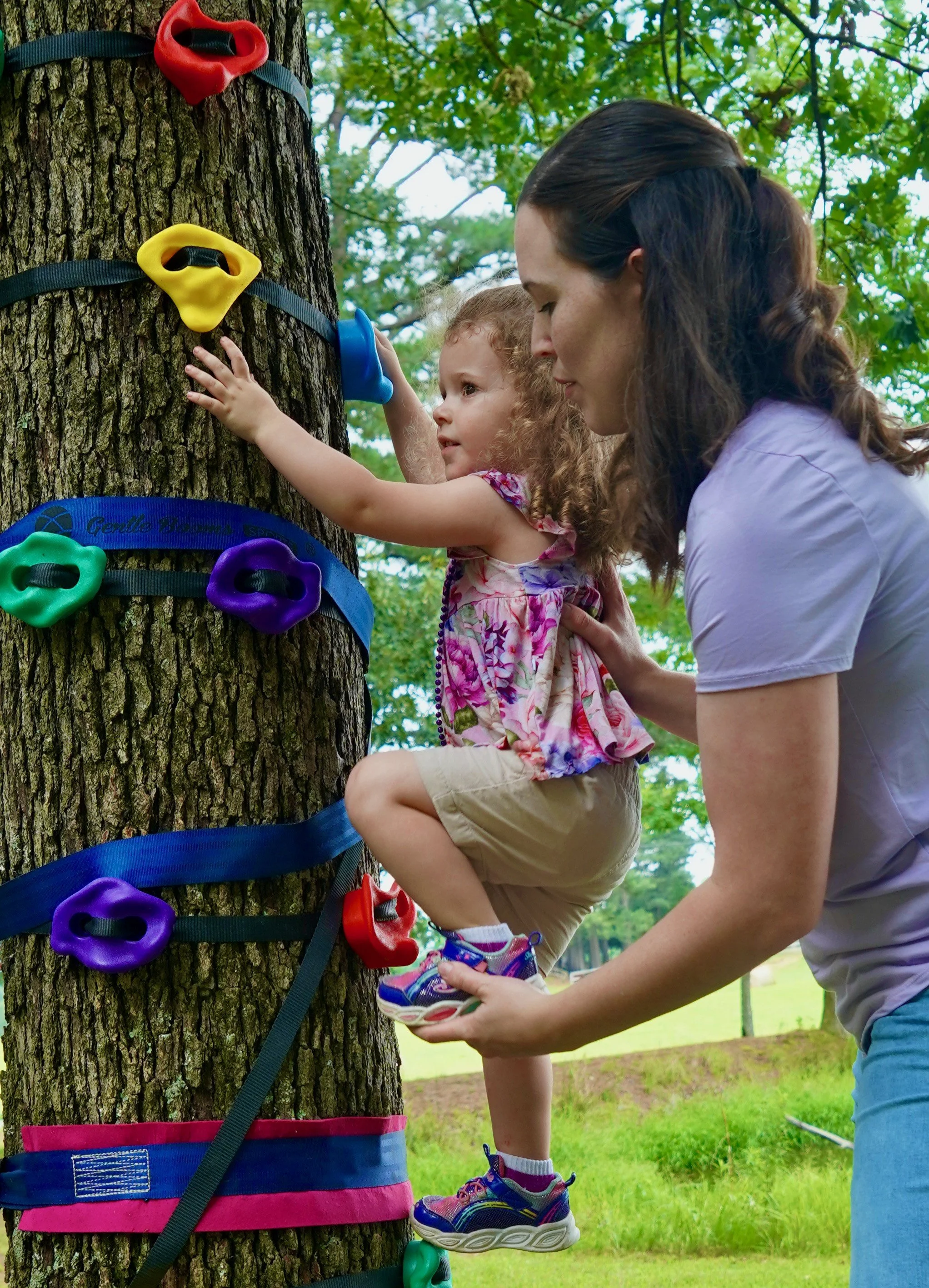 Therapist helping a child climb during an outdoor-based pediatric occupational therapy session in Mountain Home, AR.