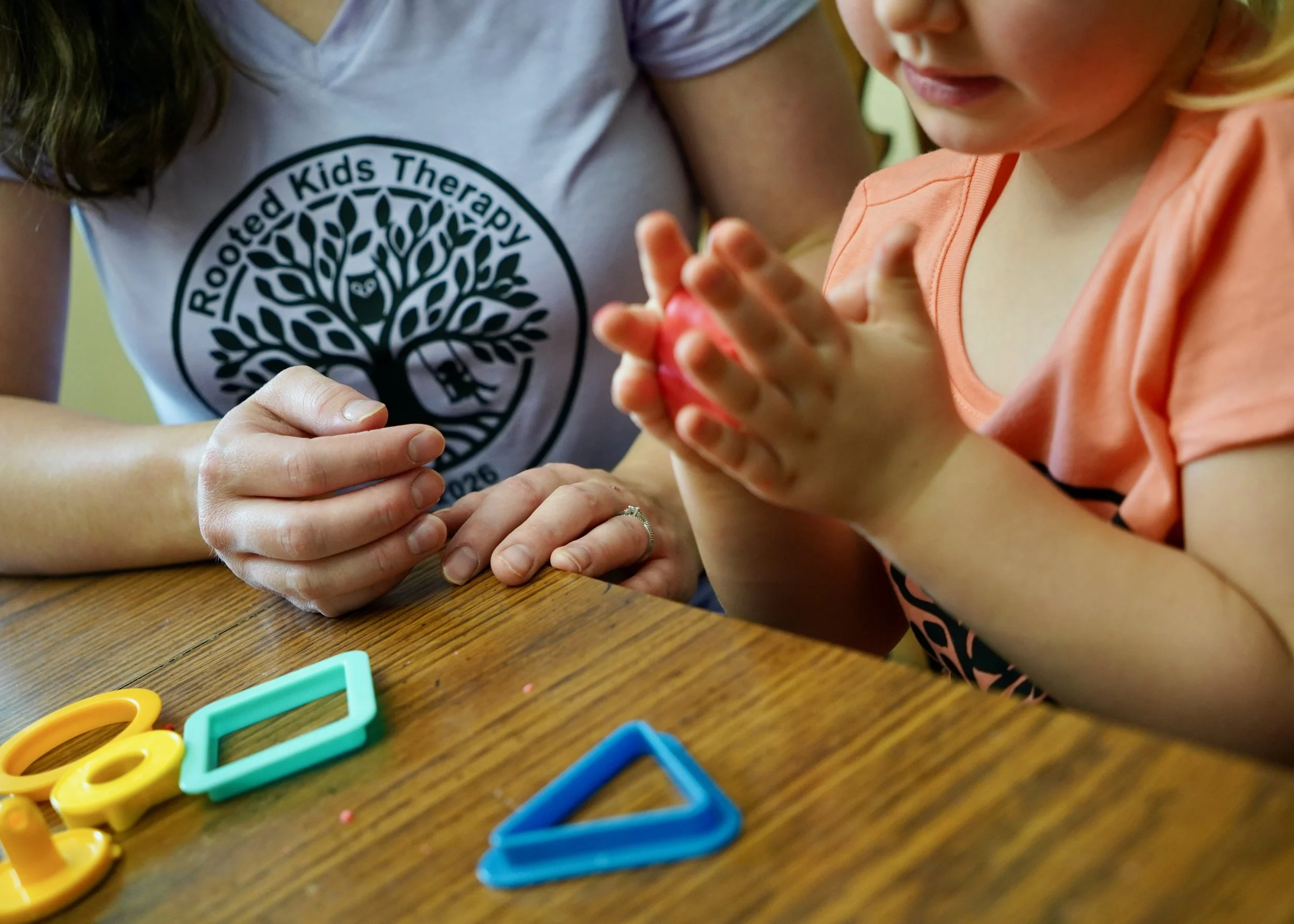 Children building fine motor skills with shape toys during a pediatric occupational therapy session at Rooted Kids Therapy.