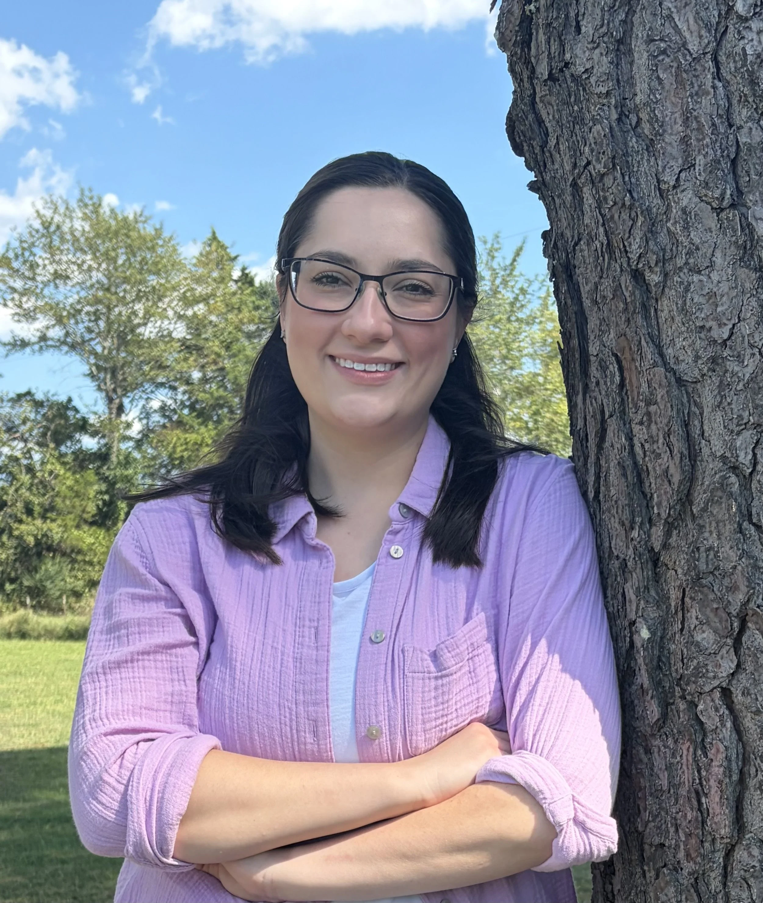 Certified occupational therapy assistant at Rooted Kids Therapy standing outdoors by a tree in Mountain Home, AR.