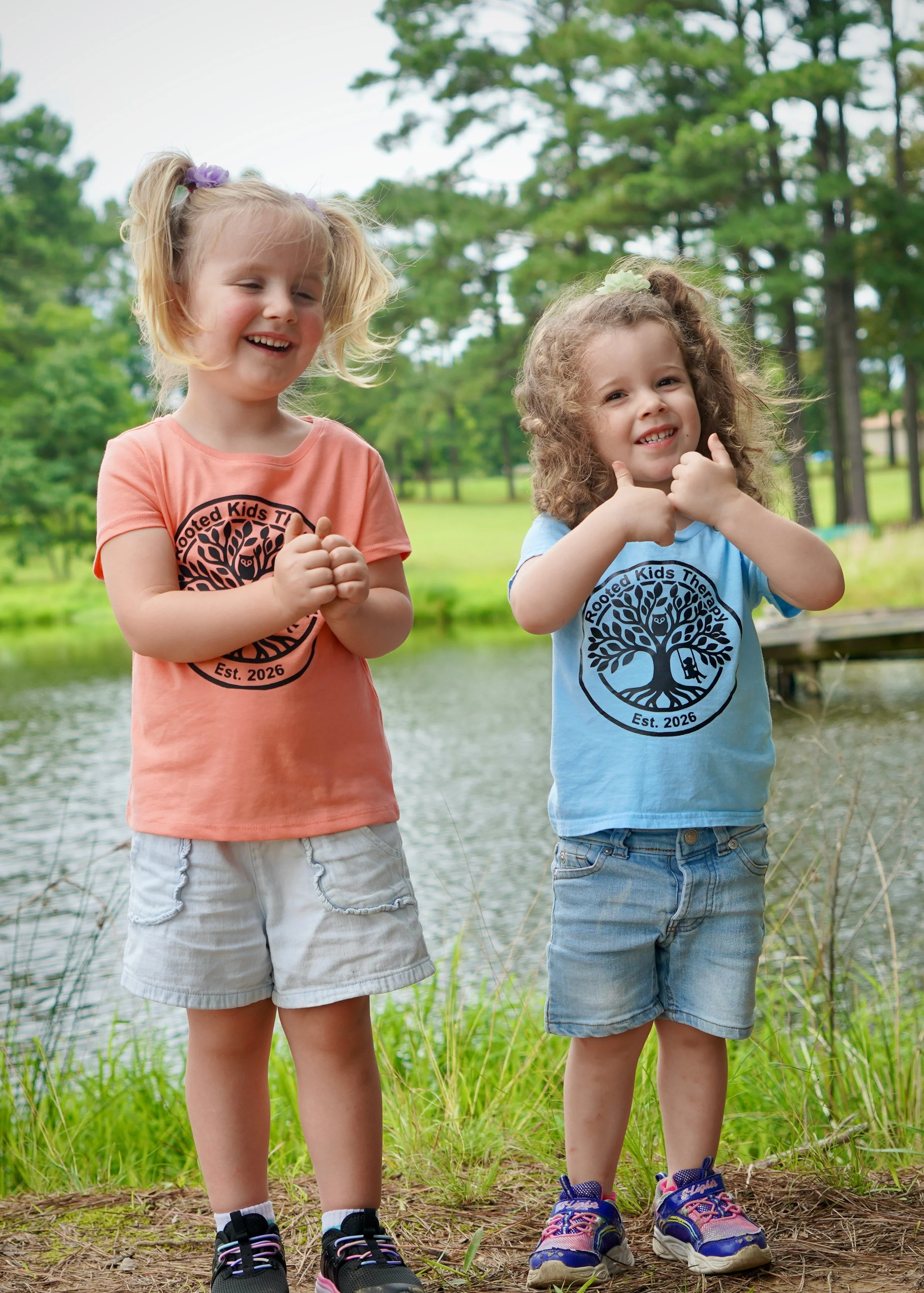 Children smiling outdoors in Rooted Kids Therapy shirts, promoting the Grow Groups outdoor enrichment program.